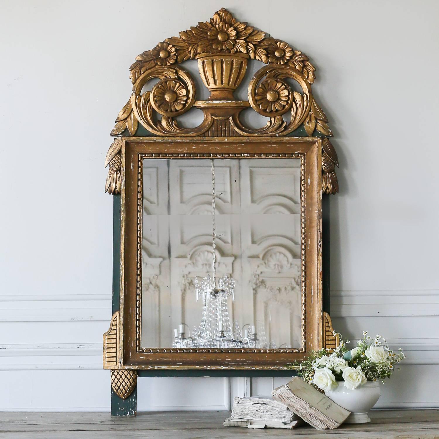 Petite vintage mirror in bright gilt against a forest green wash. The prominent crest features an urn with an intricate floral pattern spilling out and down the frame. Simple beading frames the mirrored glass. A sweet addition to a bathroom or