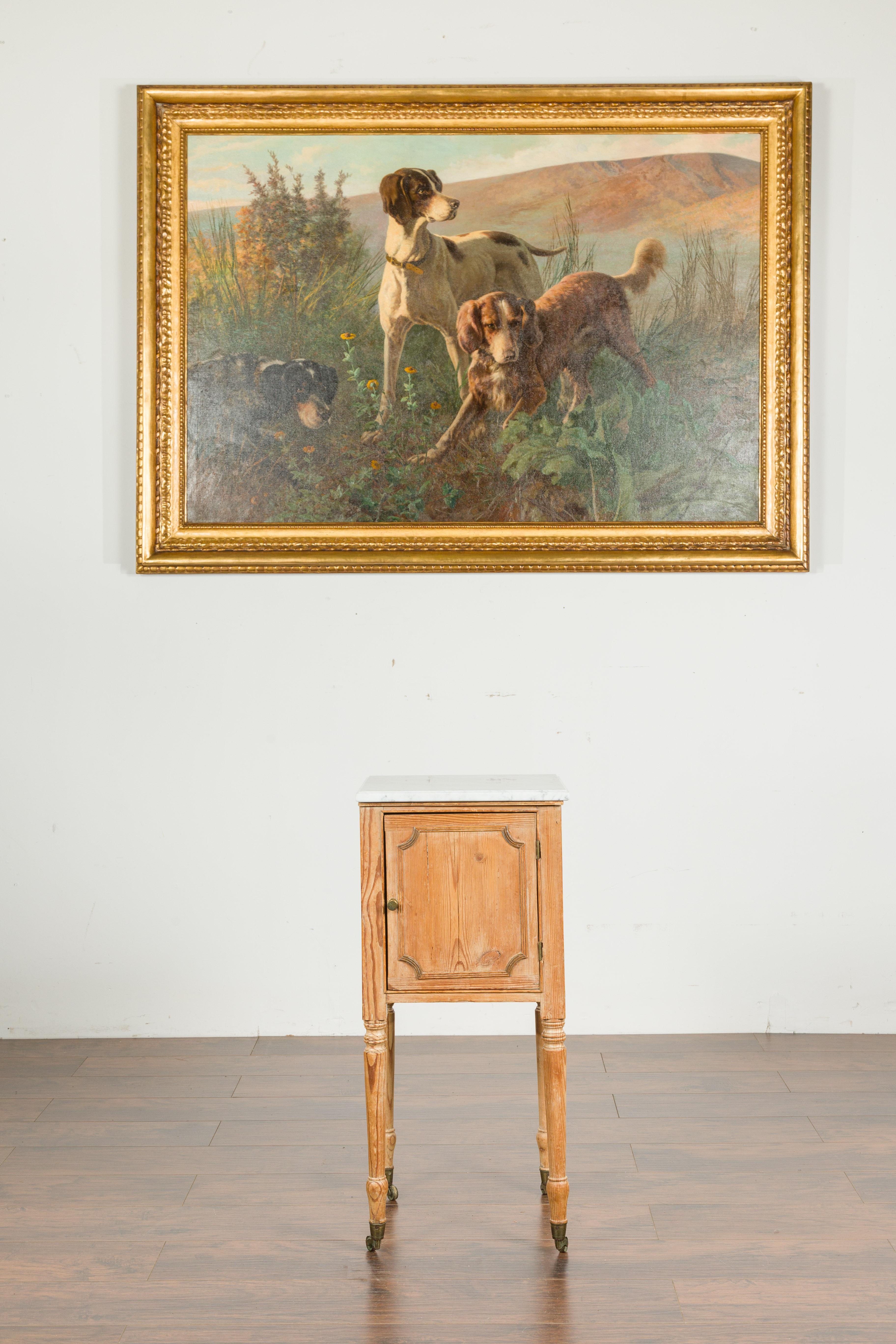 A petite English pine end table from the late 19th century, with white marble-top, single door and casters. Created in England during the third quarter of the 19th century, this petite pine table features a square white veined marble top, sitting