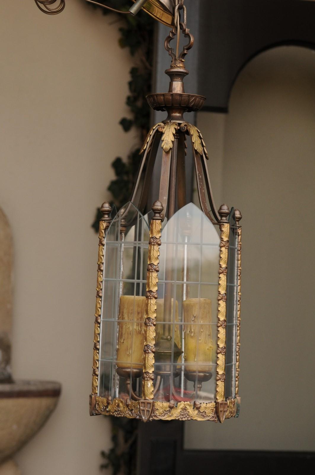 A petite English Edwardian period bronze Gothic Revival hexagonal lantern from the early 20th century, with glass panels, grape and shield motifs. Born in England in the early years of King Edward VII reign, this lovely bronze lantern features an