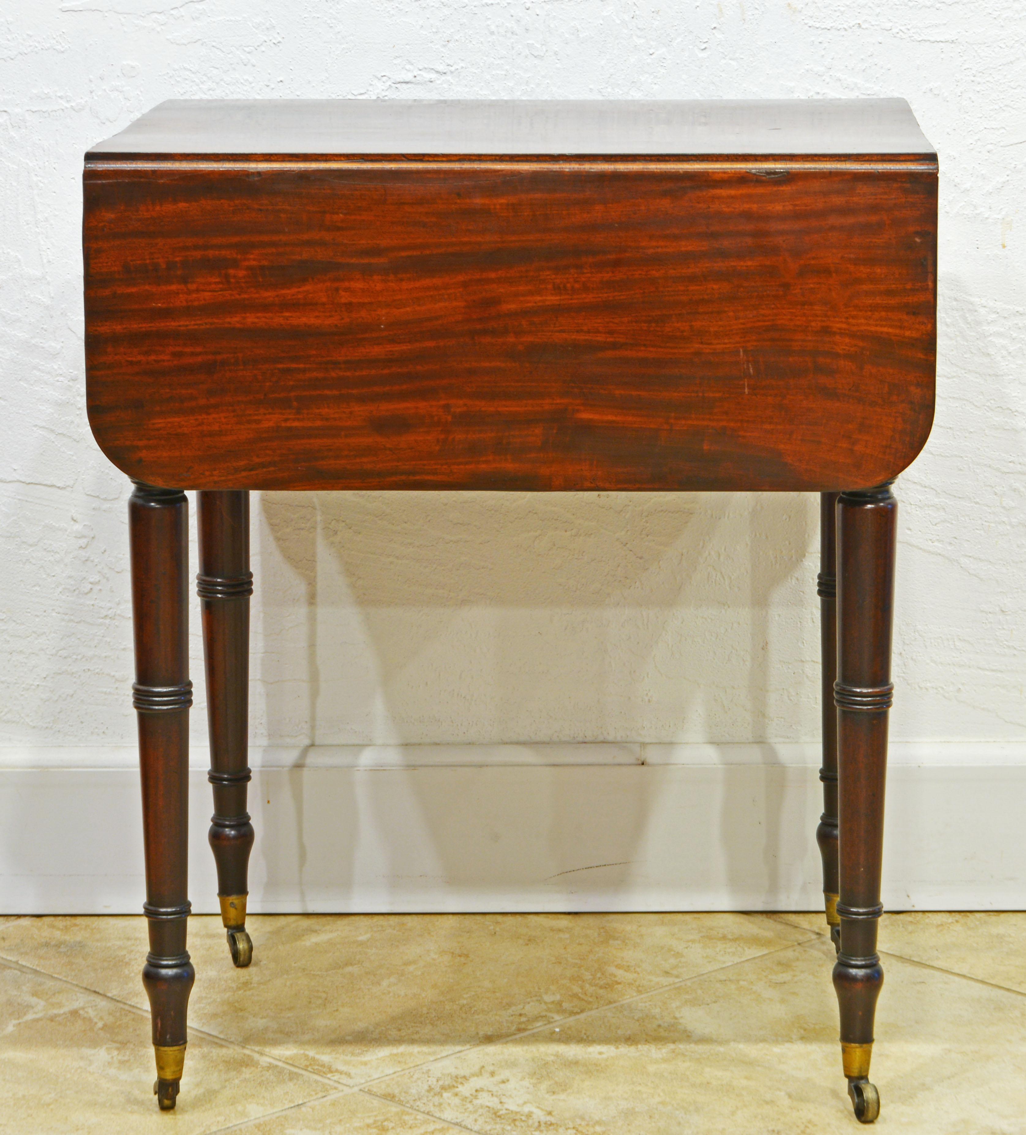 This attractive size English mahogany pembroke table feature a polished top of a deep warm color above a drawer with two turned pulls complimented by a similar simulated on the other side.resting on four round beautifully turned legs ending in