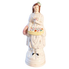 Pequeño objeto decorativo de porcelana inglesa que representa a una dama con una cesta de flores