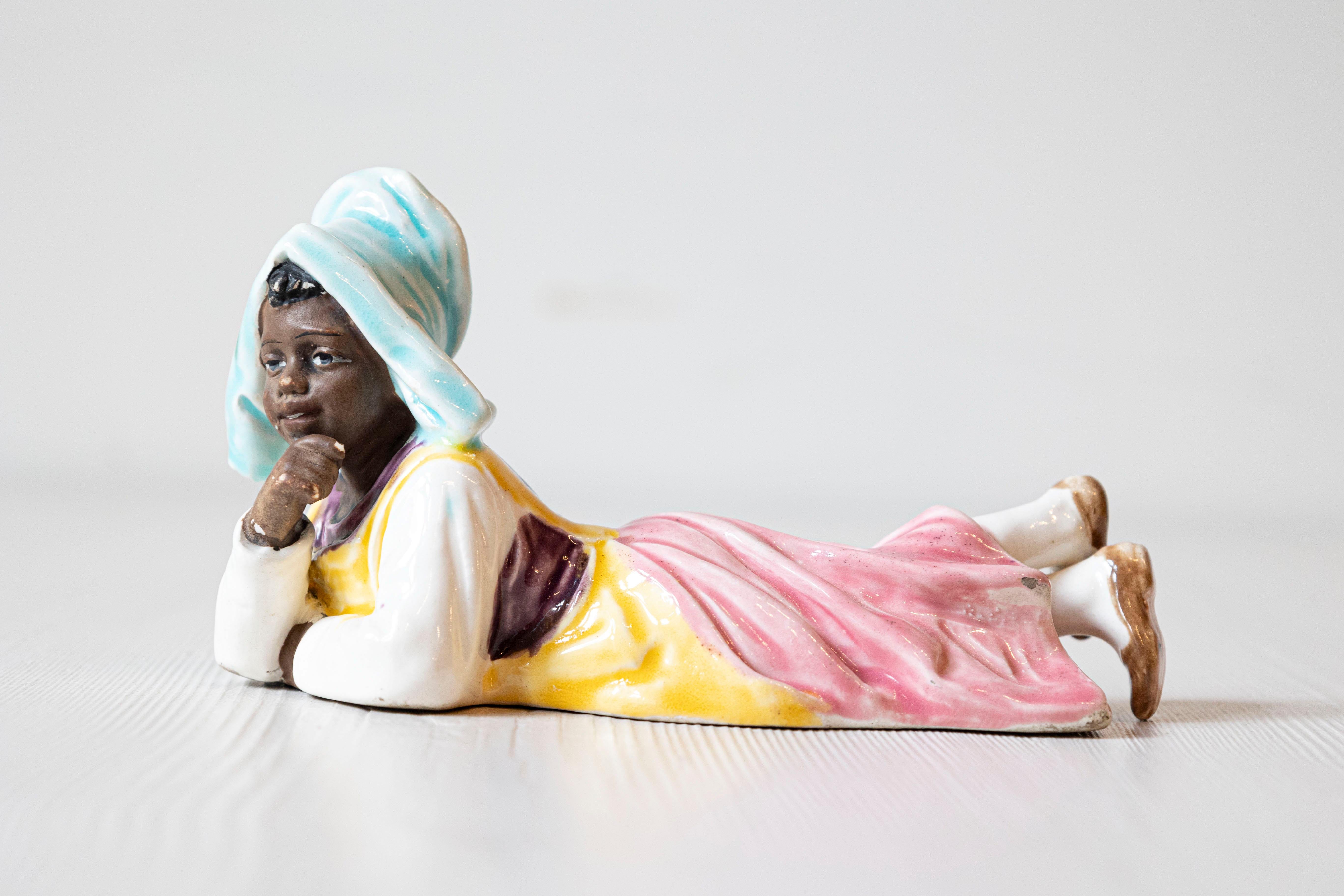 Petite figurine en porcelaine anglaise du 20e siècle, représentant une jeune fermière. Créé en Angleterre au cours du XXe siècle, ce petit objet décoratif en porcelaine nous charme par sa jolie représentation d'une jeune fermière allongée sur le