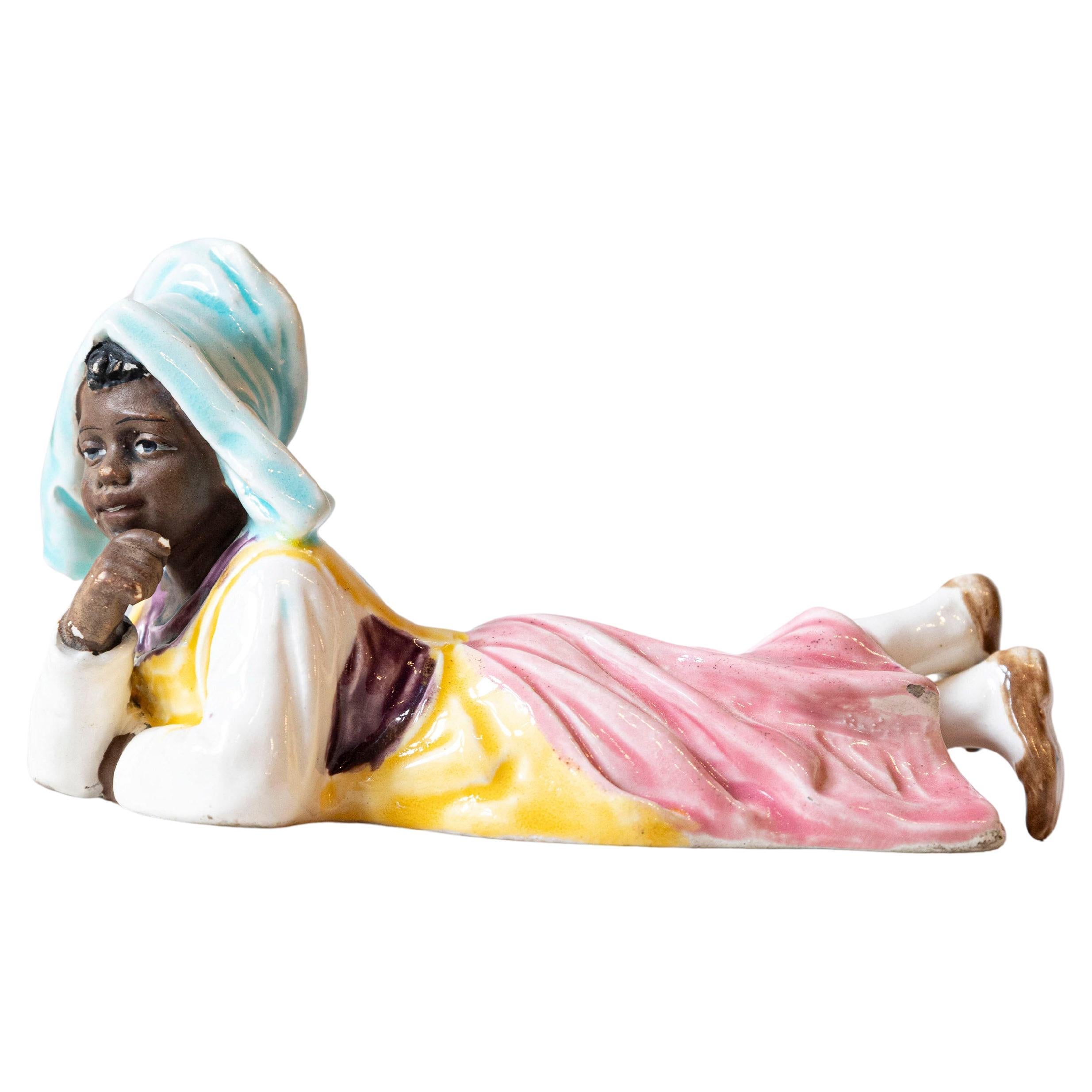 Petite English Porcelain Figurine Depicting a Young Girl Laying on the Ground