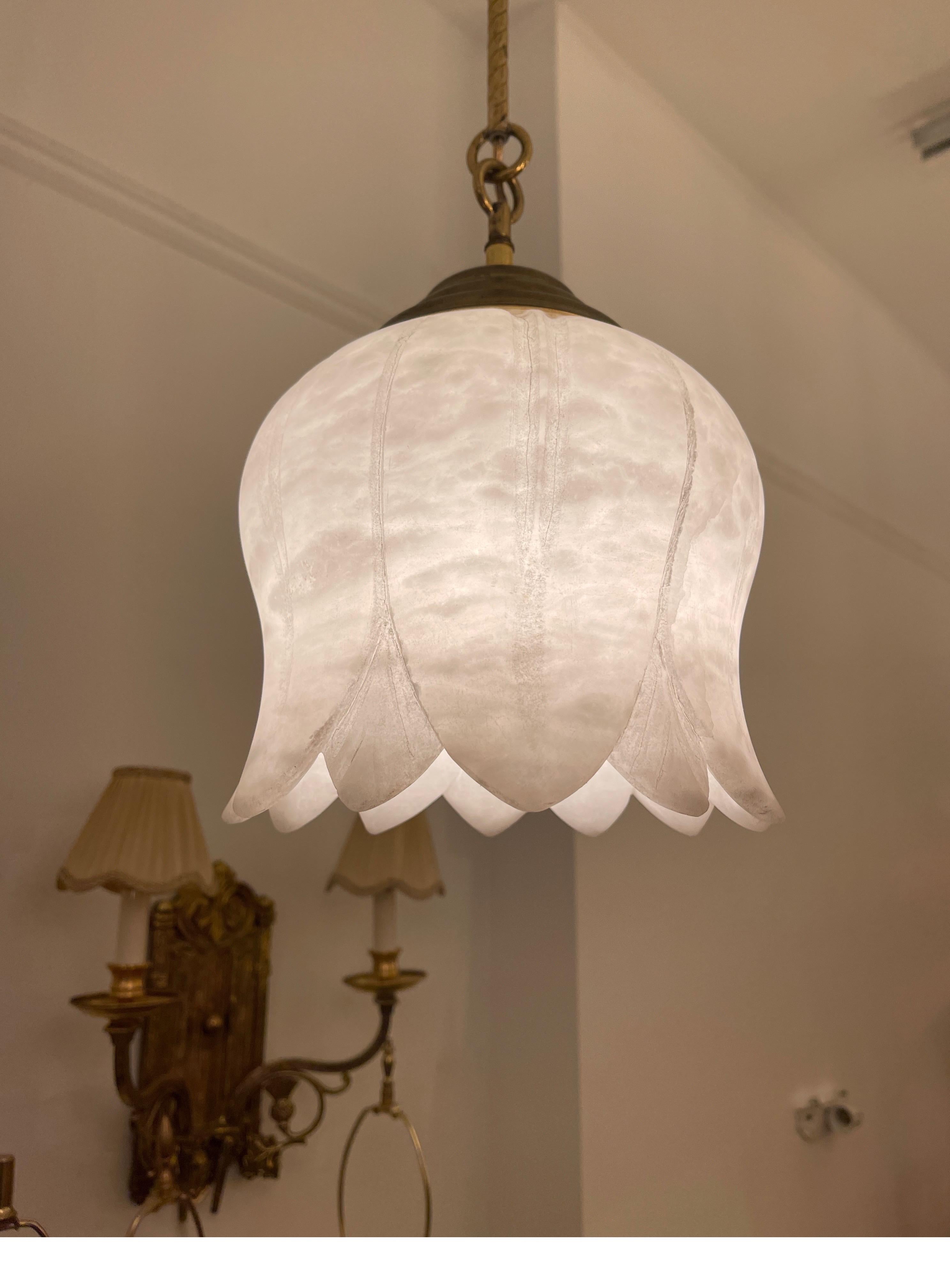 A single downward, facing flower, is mounted on, turned and reeded brass rods. One bulb illuminates the alabaster shade, which is in mineralized white alabaster.