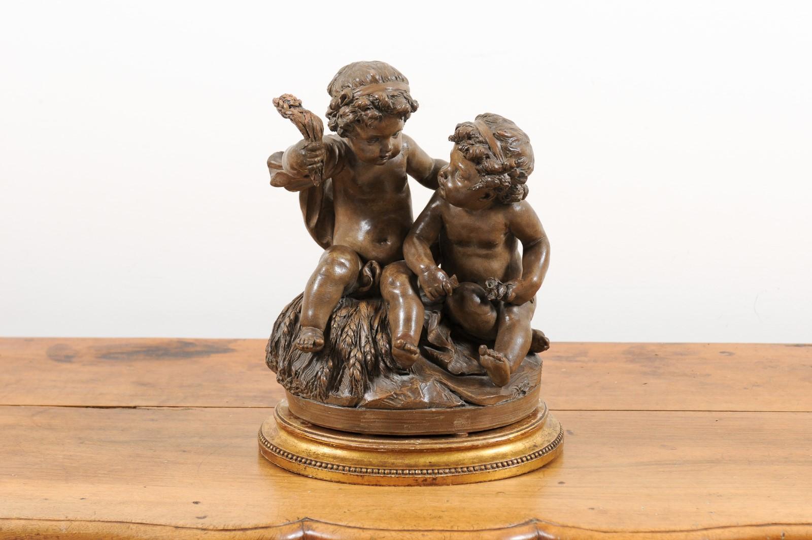 A petite French Louis-Philippe terracotta sculpture from the mid 19th century, depicting two putti on an oval base. Created in France during the second quarter of the 19th century, this petite terracotta sculpture draws our attention with its