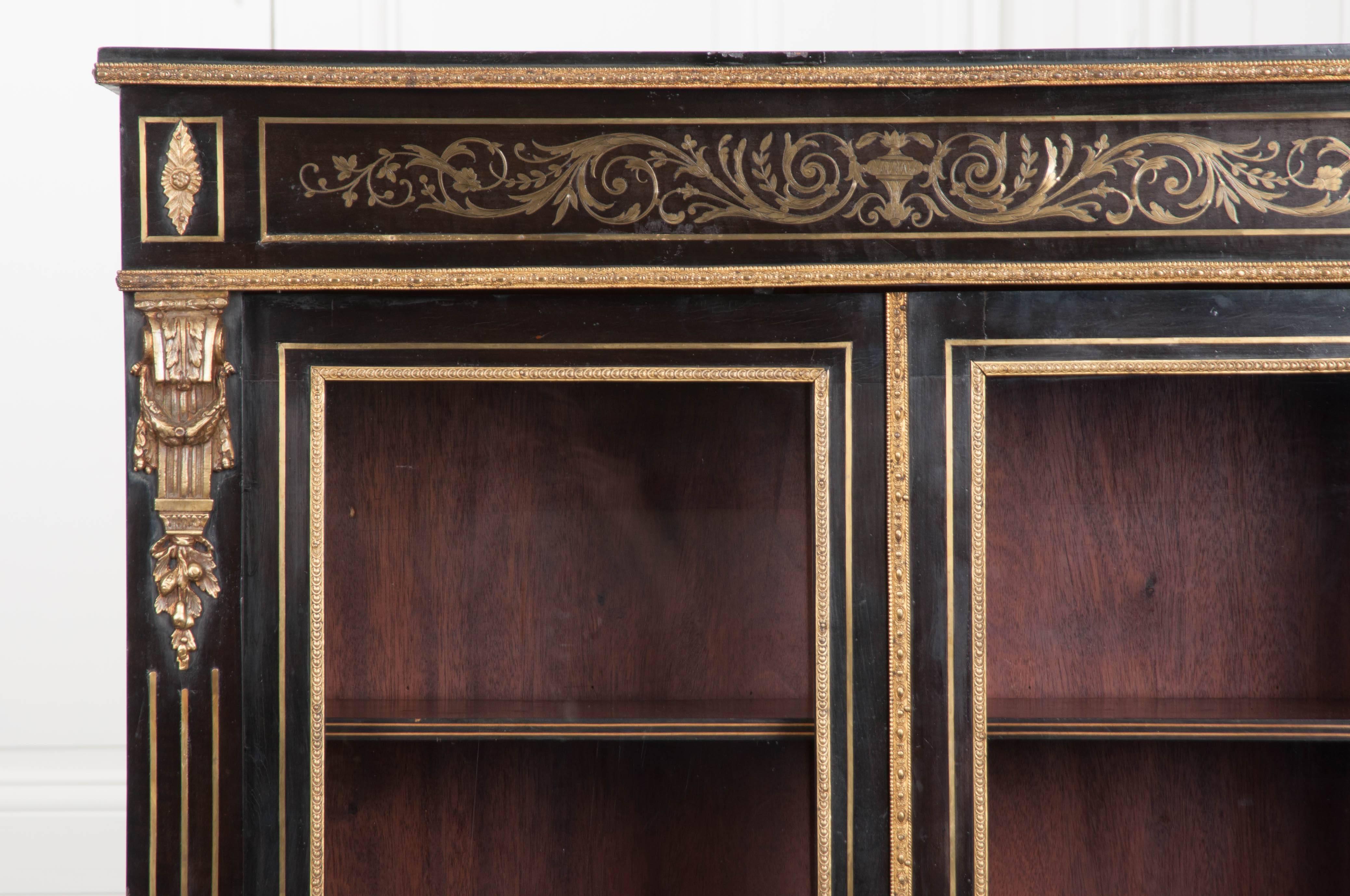 This small yet stately bibliothèque, was made in France, circa 1870, in the manner of André-Charles Boulle (1642 – 1732). It is ebonized and adorned with exceptional brass inlay or Boulle work. Elaborate ormolu inlay, depicting floral-and-foliate