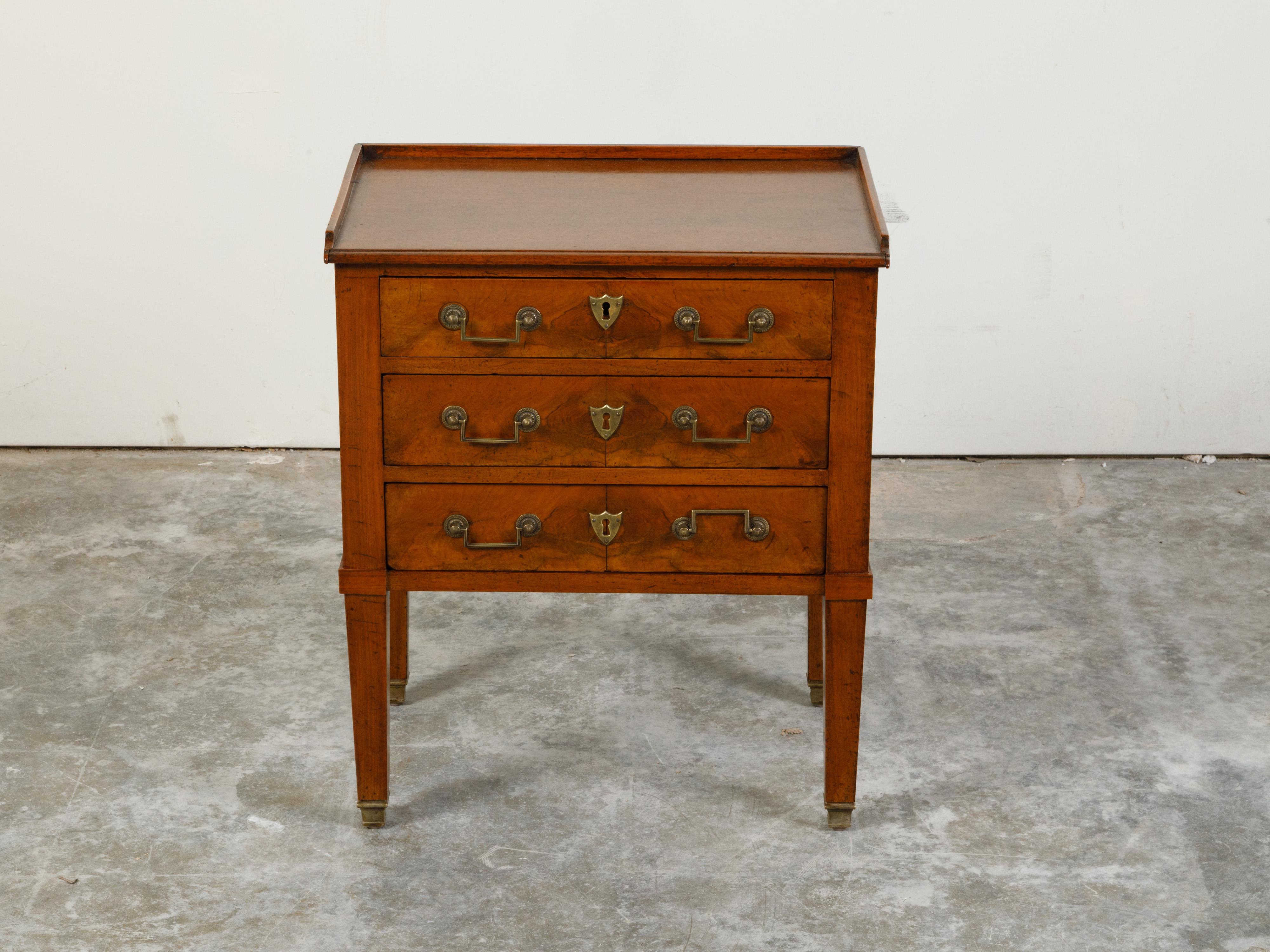 A French petite walnut bedside table from the 19th century, with three-quarter gallery and butterfly veneer. Created in France during the 19th century, this walnut nightstand features a rectangular top surrounded by a three-quarter gallery, sitting