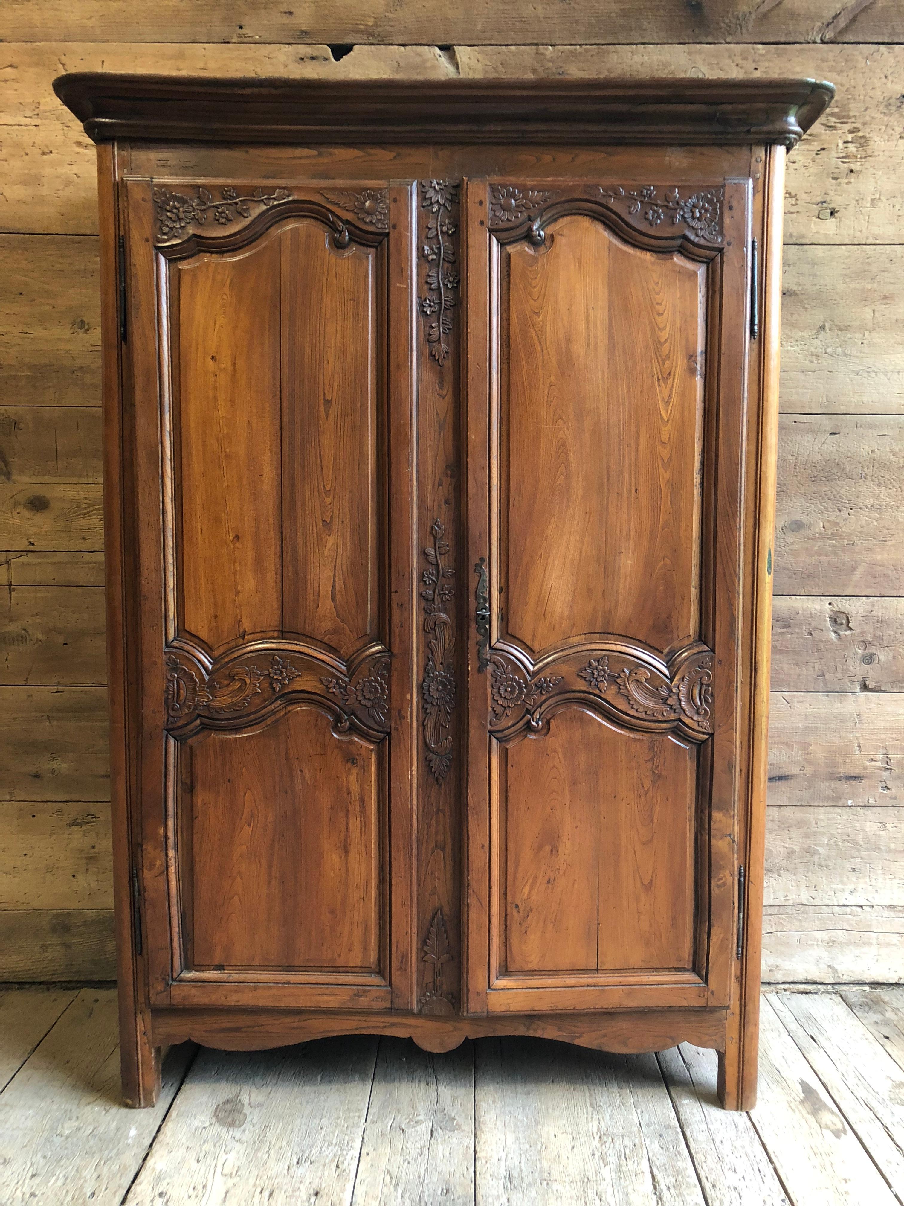 A small scale Louis XV armoire in elm wood, with two doors nicely carved with inset panels, the games carved with vines and flowers. The interior has been recently painted light gray and has 3 adjustable shelves. The piece retains its original