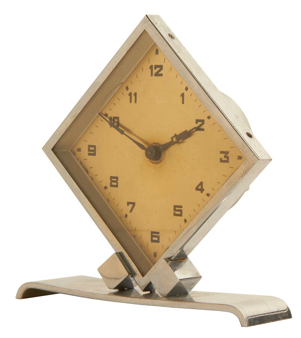 This exquisitely designed petite French geometric desk clock features a diamond shaped body with a chrome bezel supported on diamond shaped chrome supports mounted on a chrome base with curved ends. The diamond shaped face has a slight gold tone and