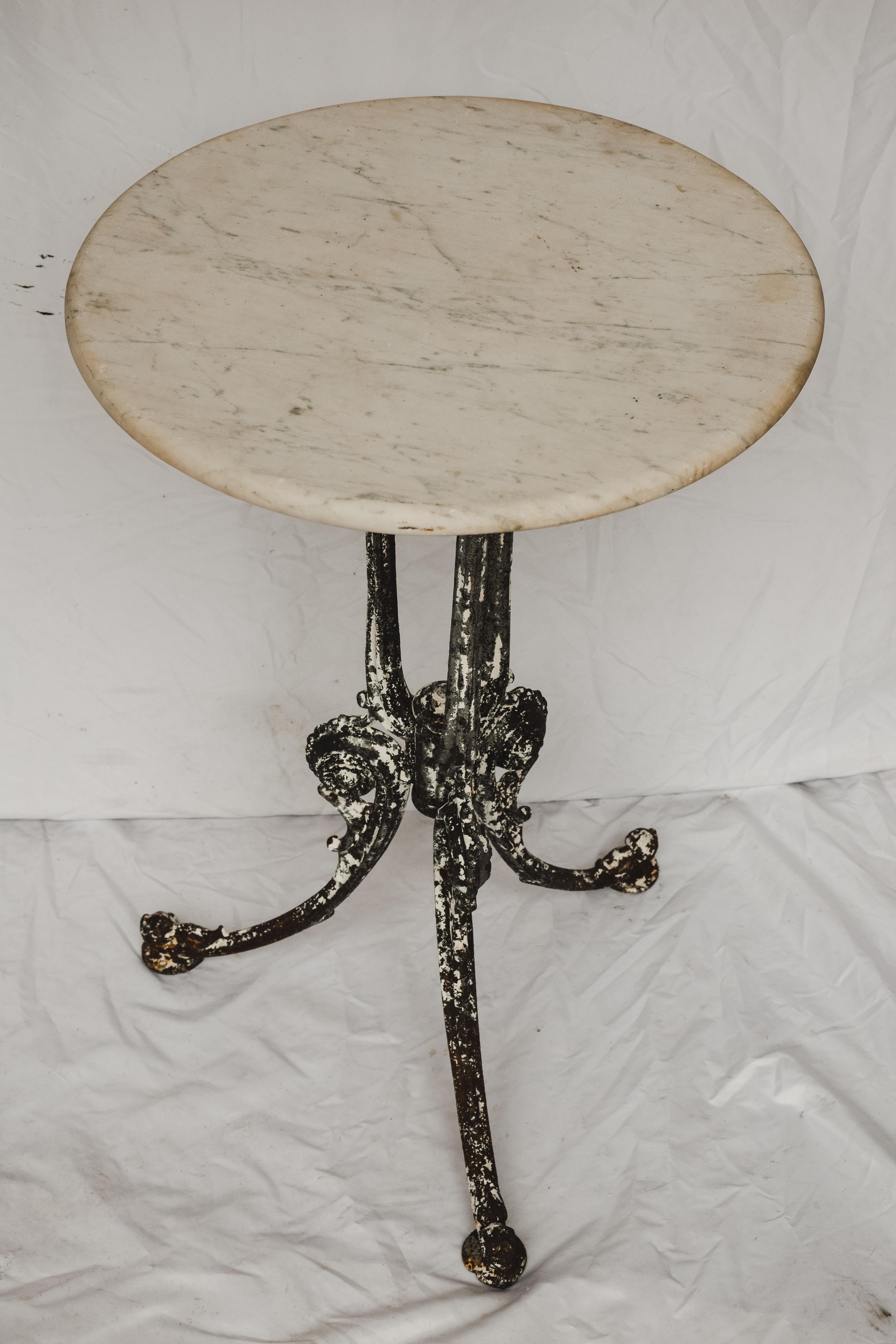 Small French Garden Table. Iron base with a black and white painted patina and a shell motif where the legs meet on the base. Would make for a charming spot to place a pot on a patio or a small table for a bathroom. 