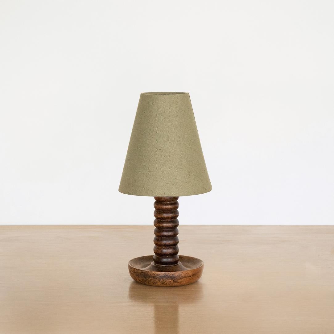 Petite wood table lamp from France, 1940s. Bobbin wood stem with circular base and original wood finish. New tapered green linen shade and newly re-wired.
 
