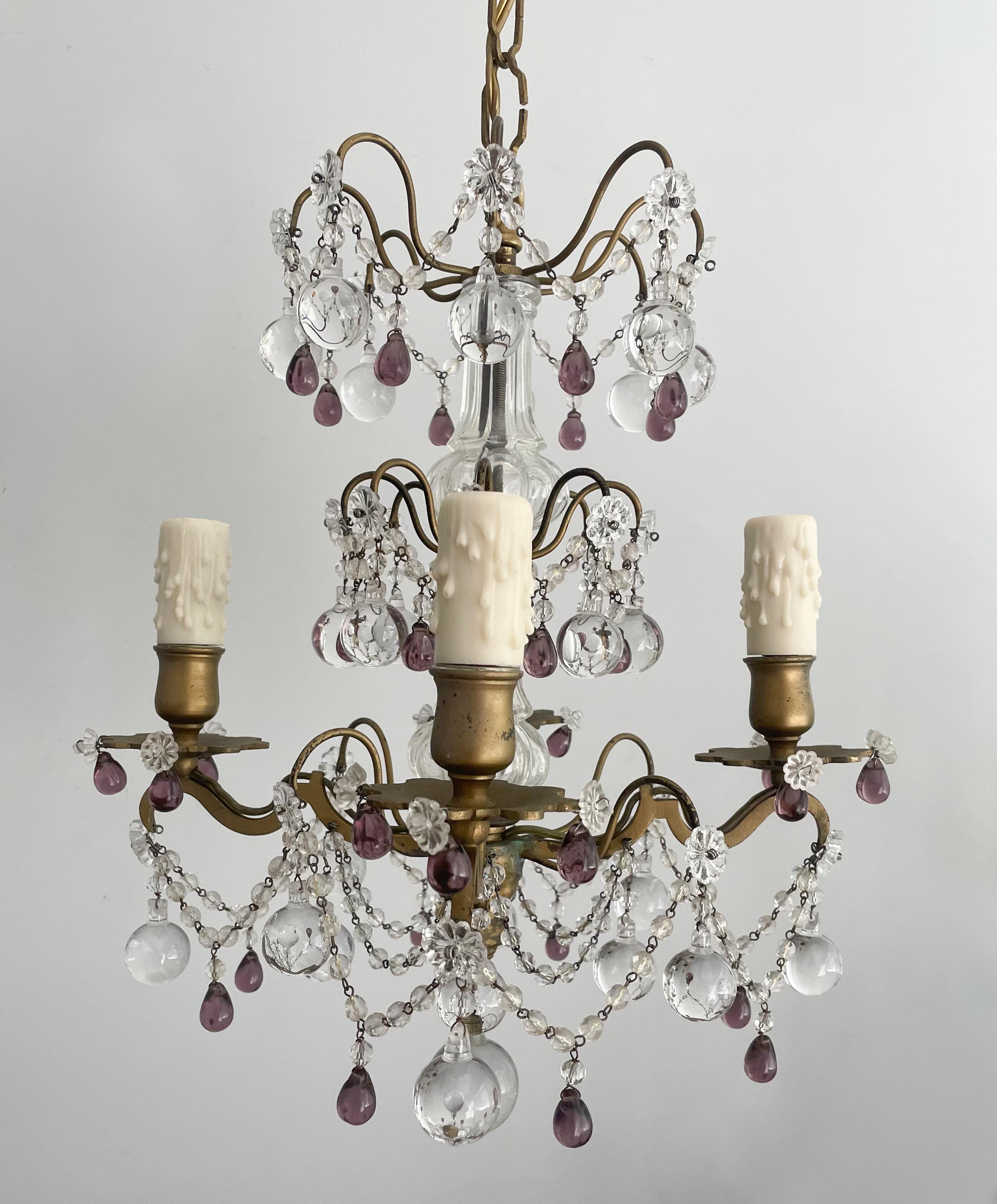 Gorgeous, petite French gilt-iron and crystal chandelier in the Versatile style. 

The chandelier features a small scale scrolled iron frame with clear and amethyst glass decorations. 

The chandelier is wired and in working condition, it