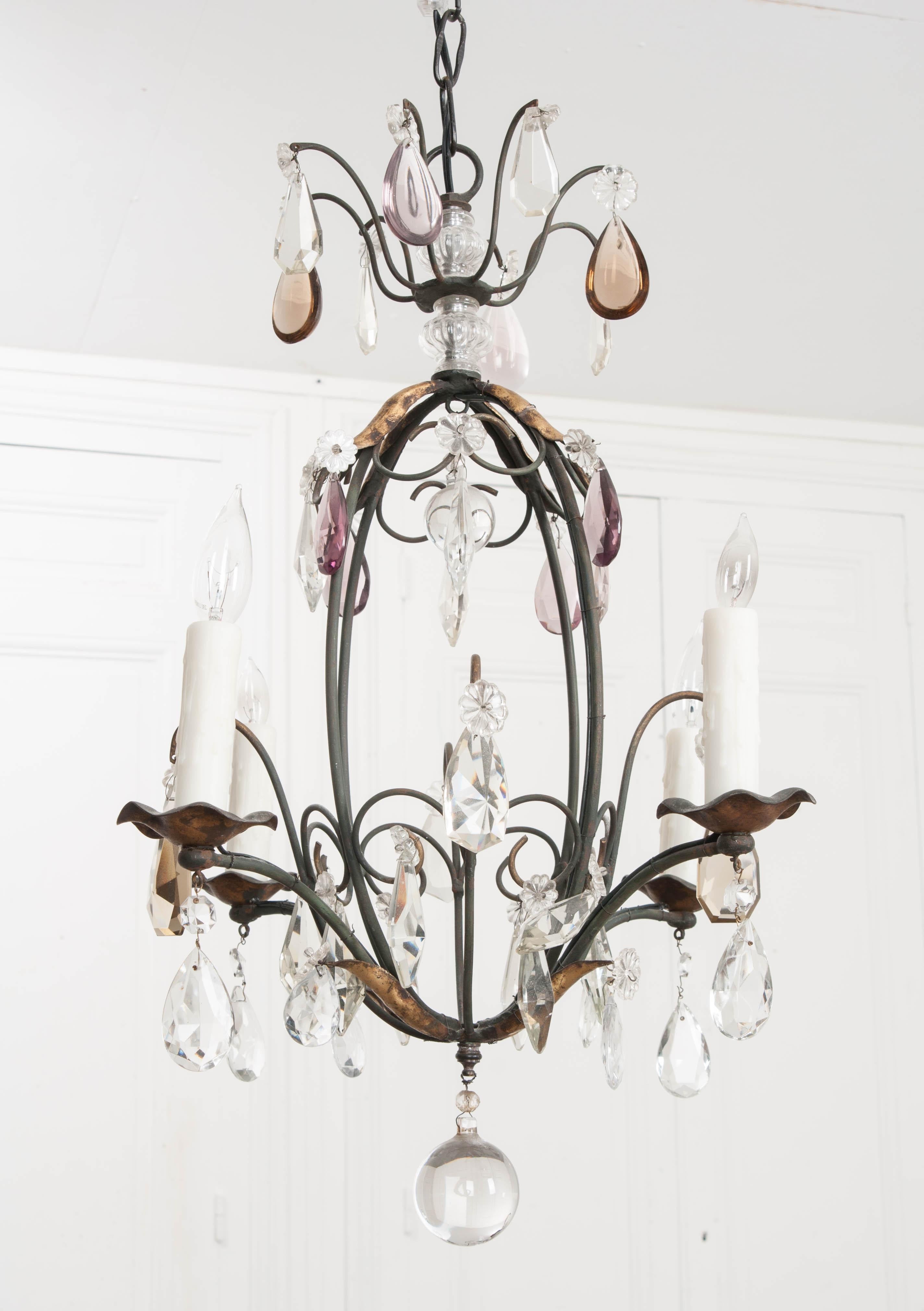 This diminutive wrought iron birdcage chandelier has clear, amethyst, and topaz cut-crystal drops of marquis and teardrop form. The wrought iron standard has applied gilt leaves and a round crystal ball drop. The whole is suspended from a chain