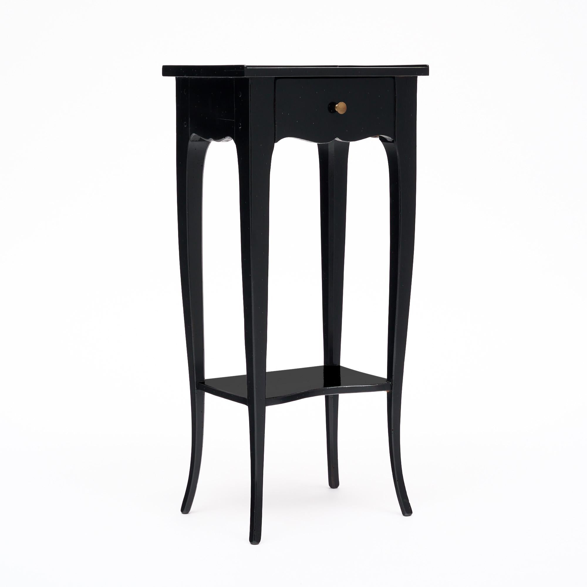 Side table from France made of wood, primarily mahogany, that has been ebonized and finished with a lustrous French polish of museum quality. There is a single dovetailed drawer with a cast brass pull. The long, tapered legs create elegance and