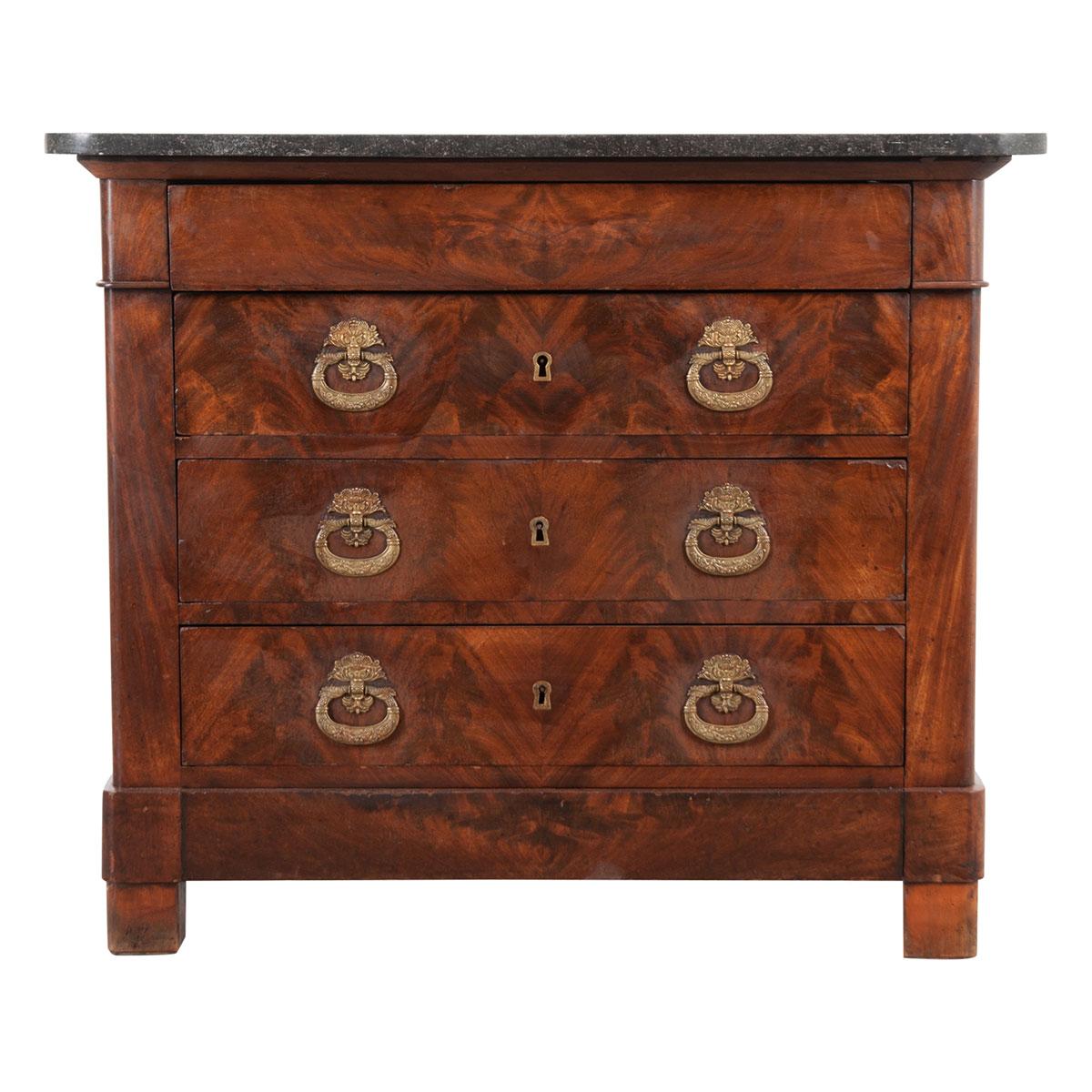 This wonderful Empire mahogany commode was created in 19th century France. Topped with a removable piece of black fossil granite with rounded front corners. The apron houses a hidden drawer without hardware, it opens easily with groves hidden on the