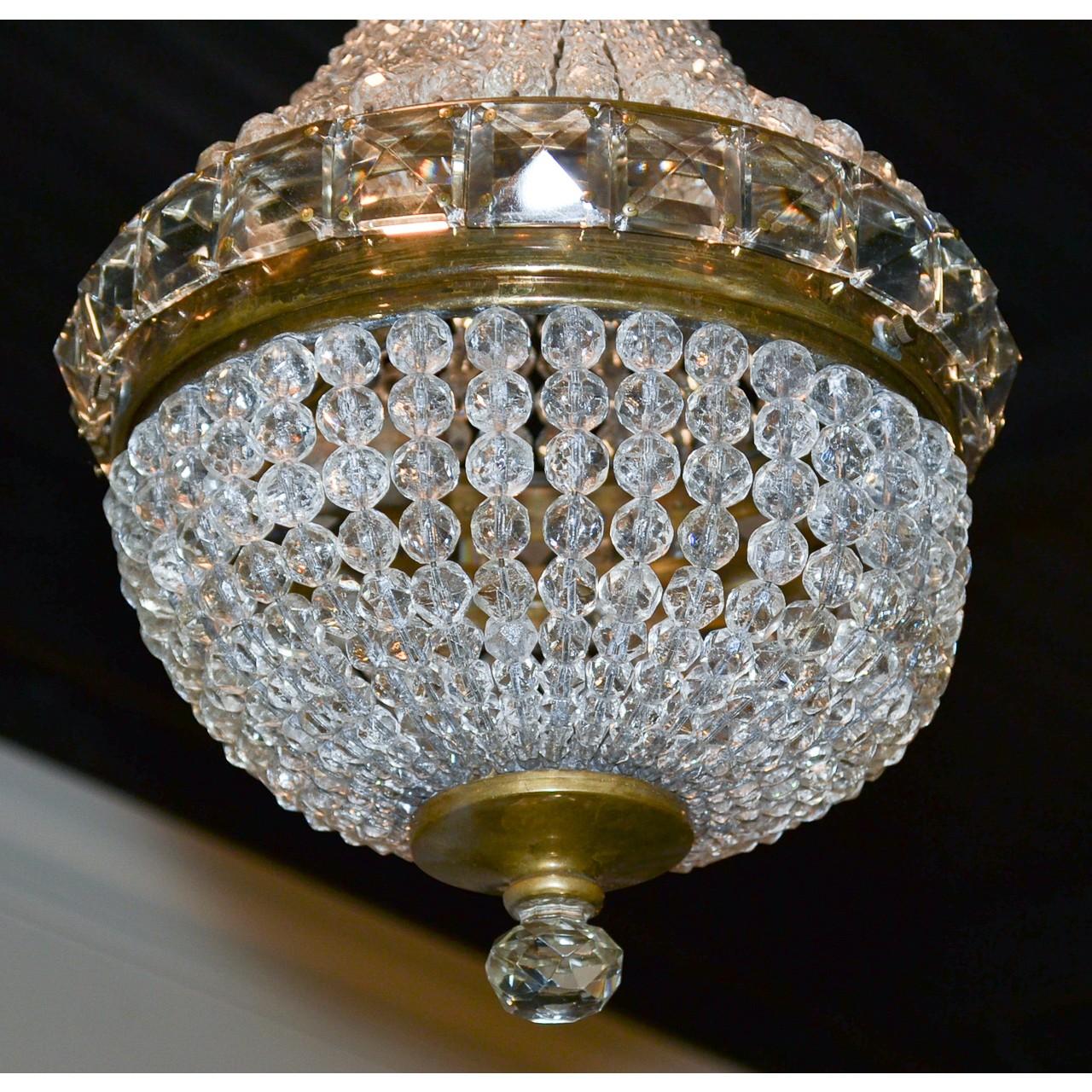 Superb small-scale French gilt bronze and crystal basket chandelier. The acanthus motif and fluted bronze canopy above a crown and central band inset with pyramidal-shaped cut crystal prisms. Embellished perfectly with multiple strands of cascading