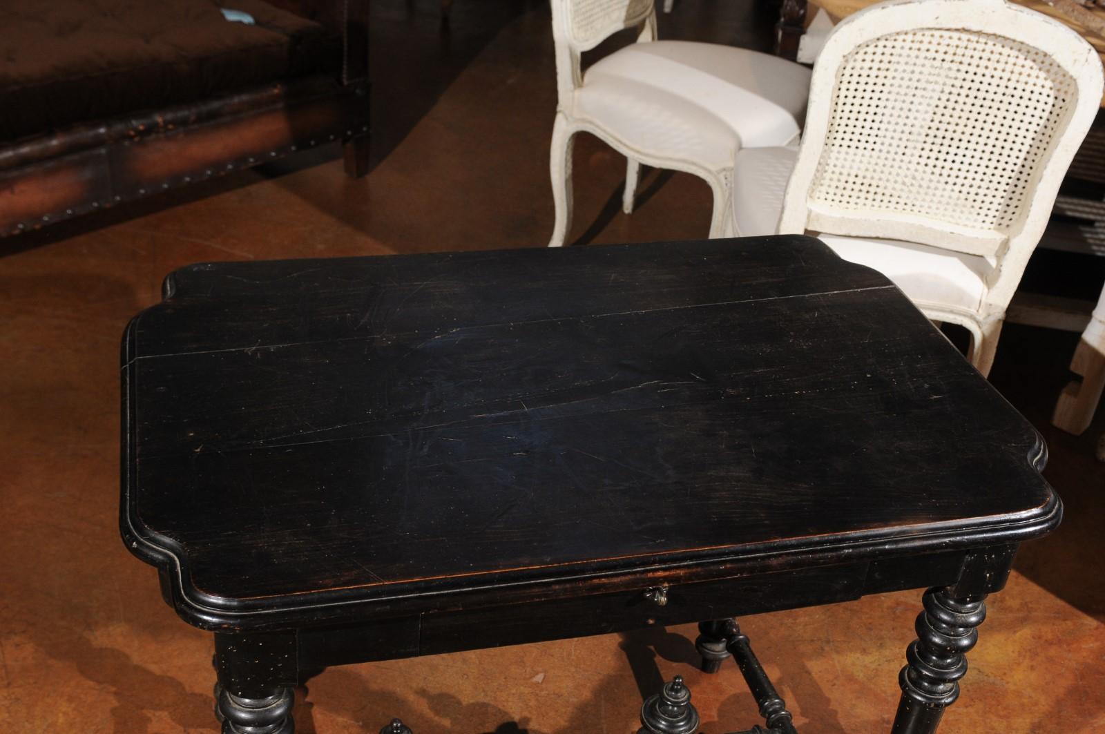 A petite French Louis XIII style ebonized wood side table from the 19th century, with single drawer, turned legs and cross stretcher. Born in France during the 19th century, this charming side table or desk features a rectangular top with curving