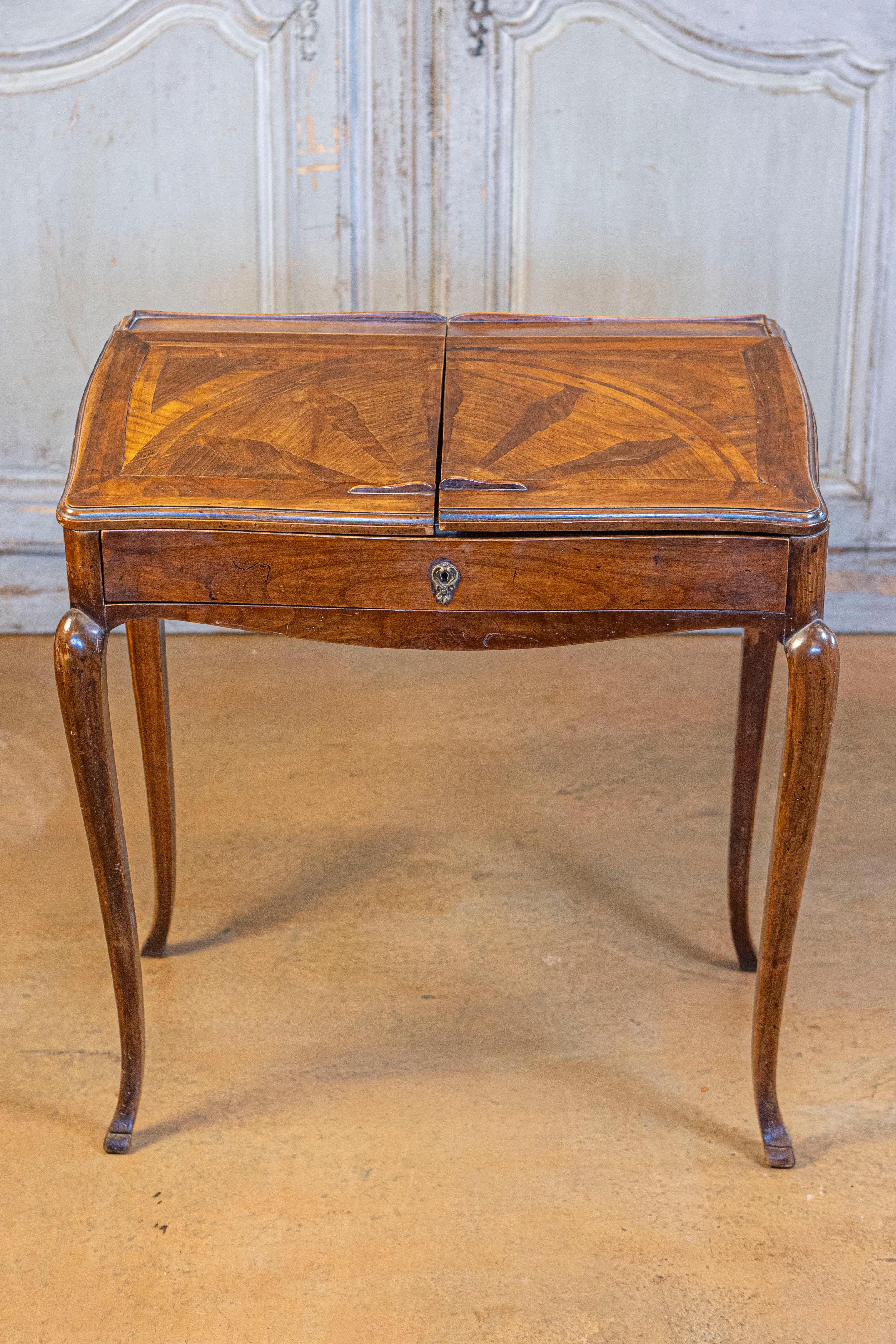 A stamped French Louis XV style small walnut slant-front desk with sliding inlaid panels, long drawer and inner compartments from the early 19th century. This petite French desk was born during the Napoleonic years, yet decorated with the curvy