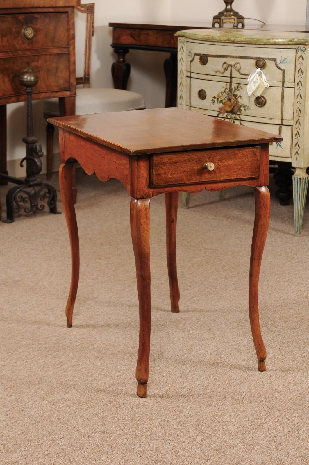 The petite French Louis XV side table in walnut with rectangular one piece top, carved shaped apron below with drawer and cabriole legs ending in hoofed feet. The top has been replaced at a later date.