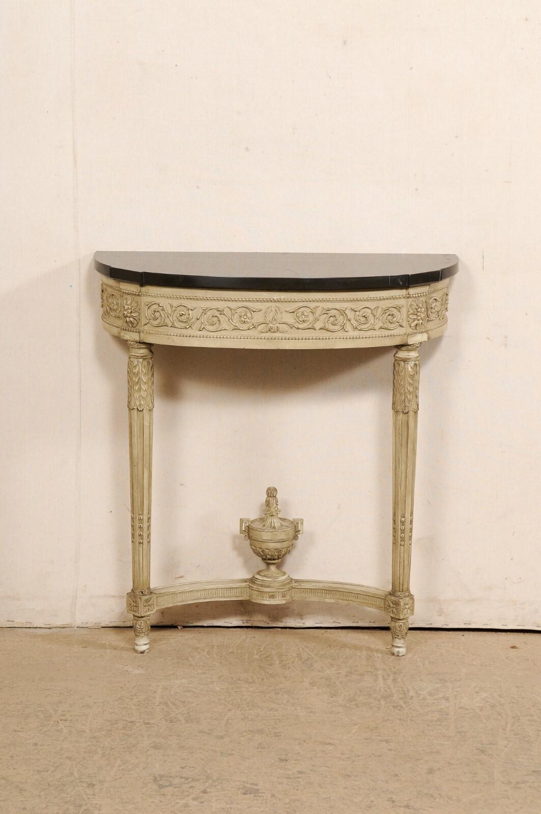 A French Neoclassic style console table, with marble top, from the early 20th century. This small-sized antique table from France features an oblong, demi-shaped marble top with blunt/canted projections at forward corners, which rests atop an apron