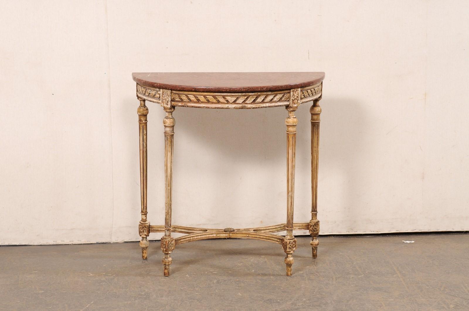 A small-sized French carved-wood demi console table with marble top, from the 19th century. This antique table from France has a half-moon shaped marble top which rests upon the apron which is carved in a ribbon motif with are adorn with squared