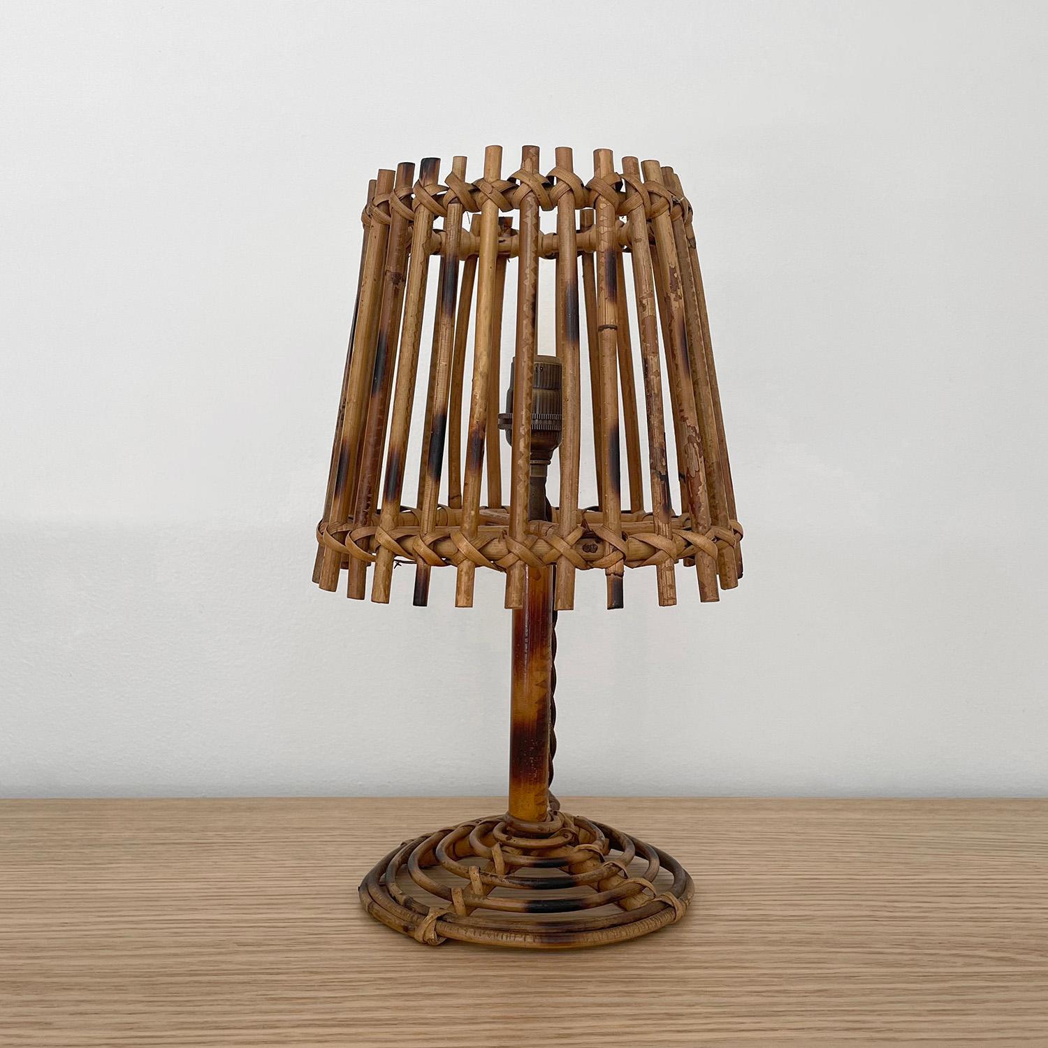 Petite French rattan lamp
Shade is comprised of vertical reeds 
Sculpted spiral base 
Natural color variations throughout
Patina from age and use
Newly rewired silk french twist cord 
Single socket candelabra base bulb 
Last photo is for reference