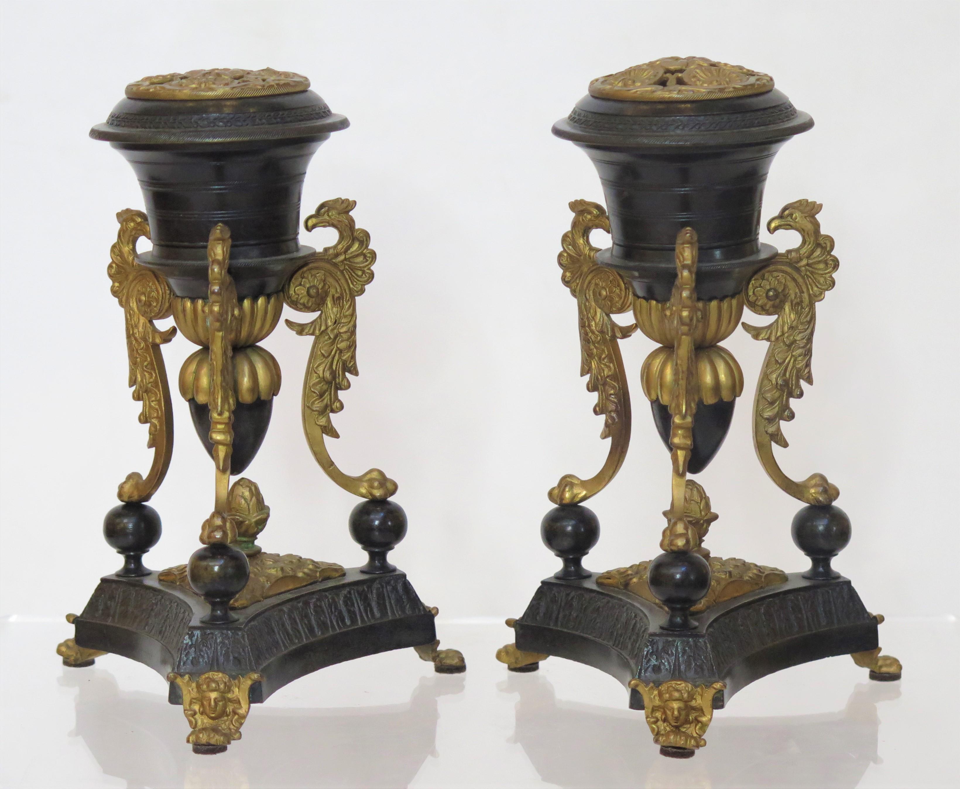 a small scale / petite pair of elegant 19th century French Restoration (1814-1830) patinated and gilt bronze brule-parfums / cassolettes / censer (incense burner), triangular tripod base with gilt feet below classical masks / faces, urn shaped