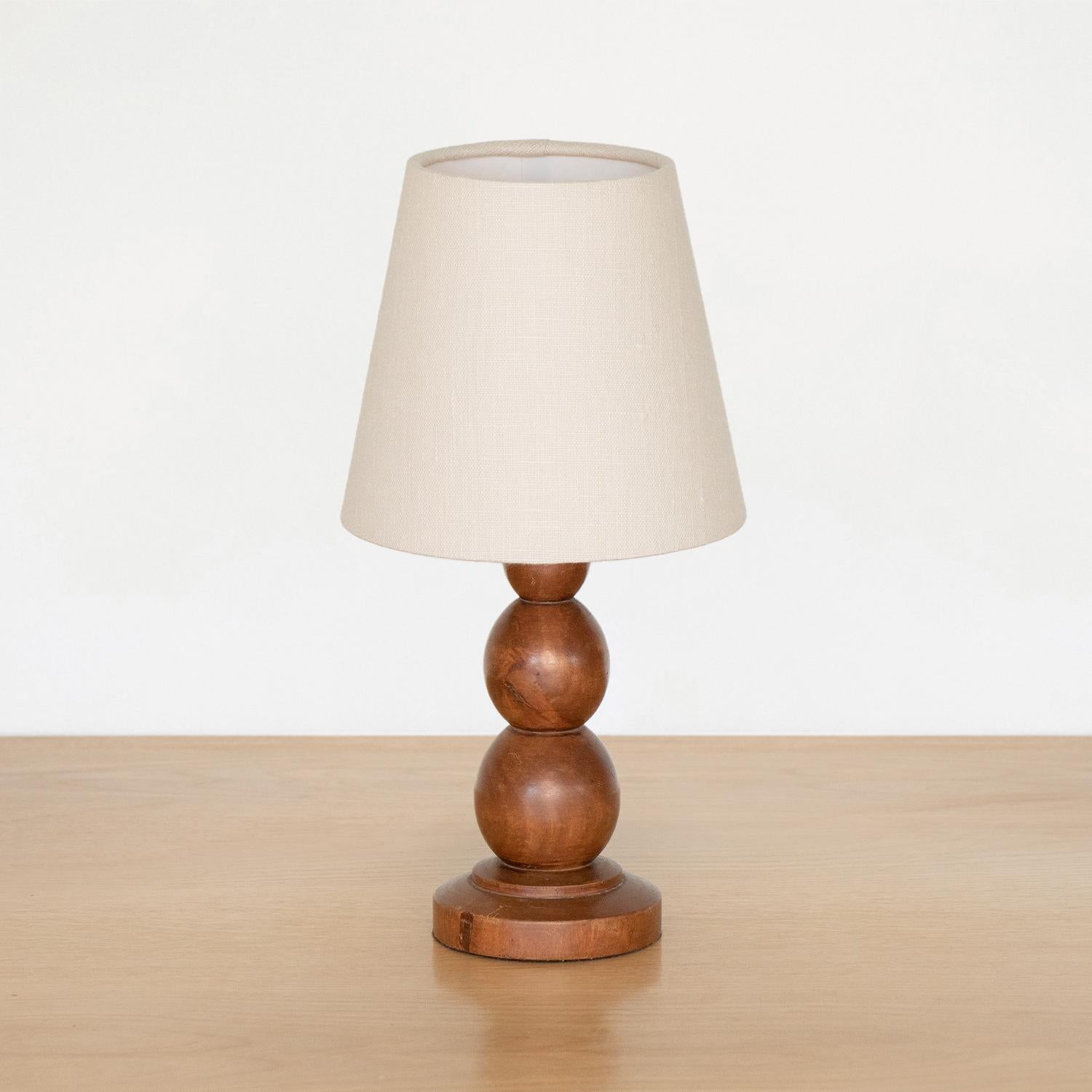 Petite wood table lamp from France, 1940s. Stacked ball forms with circular base and original wood finish. New linen shade and newly re-wired.
