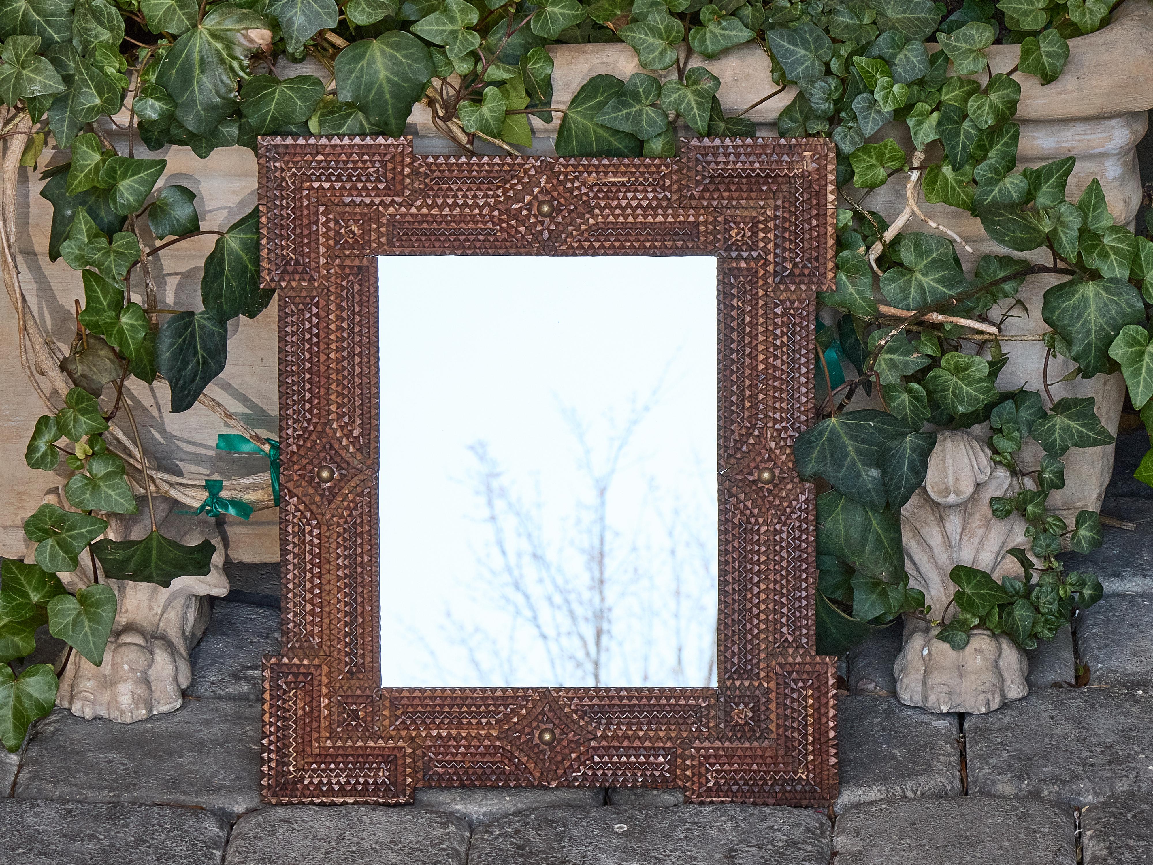 Petite in scale but bold in personality, this early 20th-century French Tramp Art mirror delivers hand-carved intricacy in a size that’s easy to place. Crafted circa 1900, the geometric frame is built up from layers of chip-carved wood with stepped