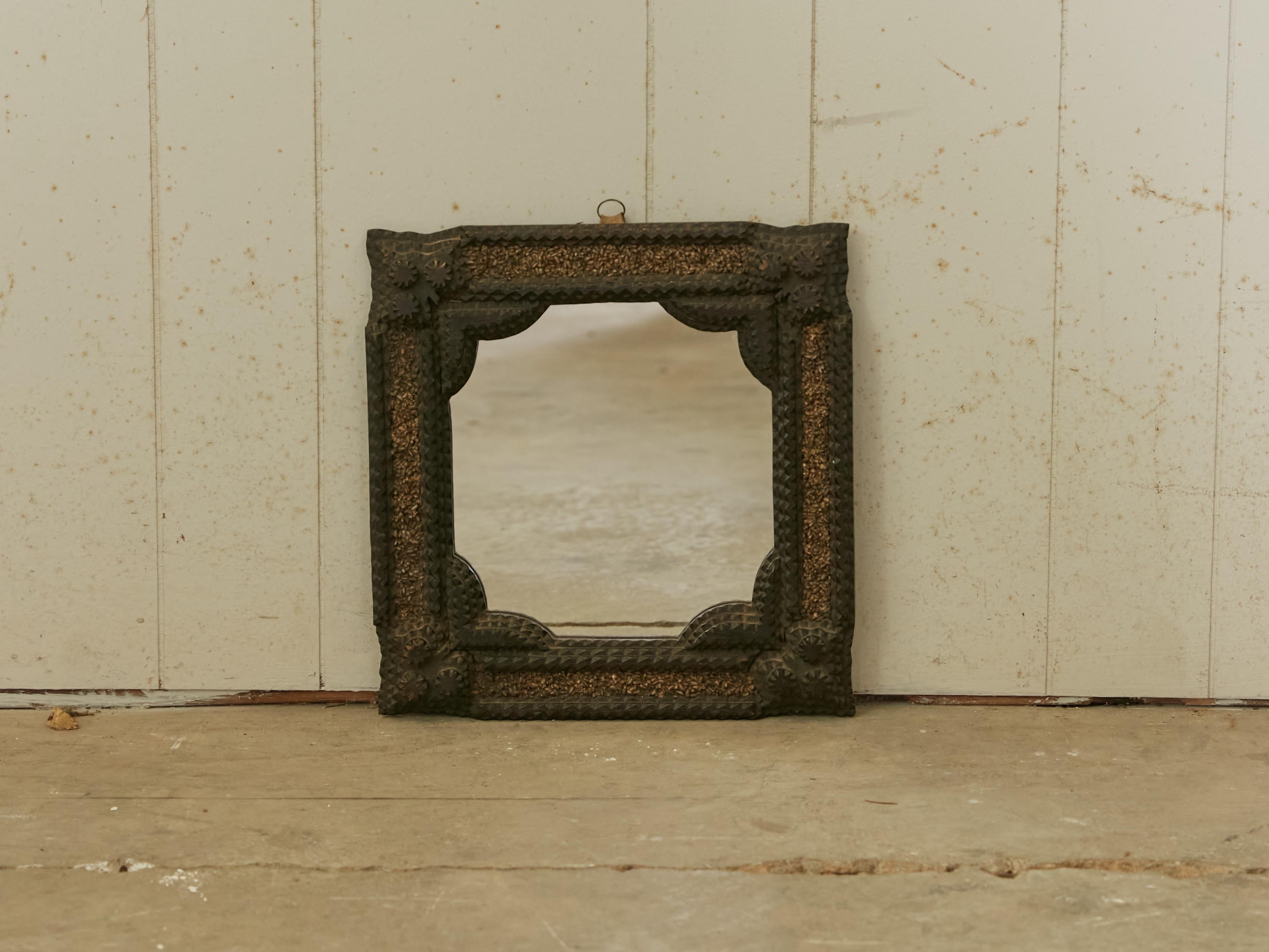 A petite French Turn of the Century Tramp Art wooden mirror from the early 20th century with hand-carved frame and raised motifs. Created in France at the Turn of the Century which saw the transition between the 19th to the 20th, this wall mirror