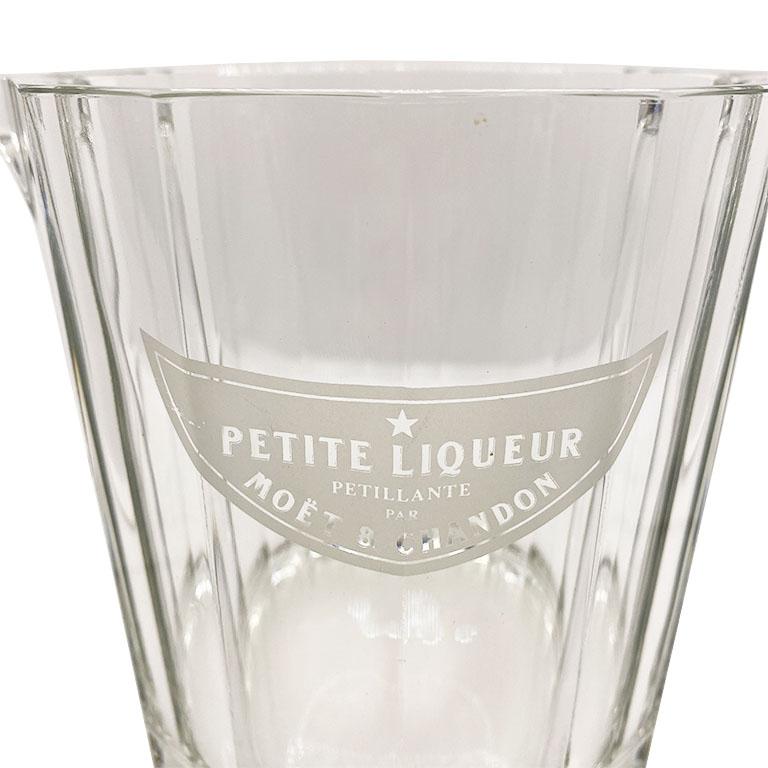 A small glass french Moët & Chandon ice bucket. This petite ice-bucket or wine cooler will be a classical touch to your bar or table. Created from glass, the bucket has two small glass handles on the sides. At the front, it reads Petite Liqueur Par