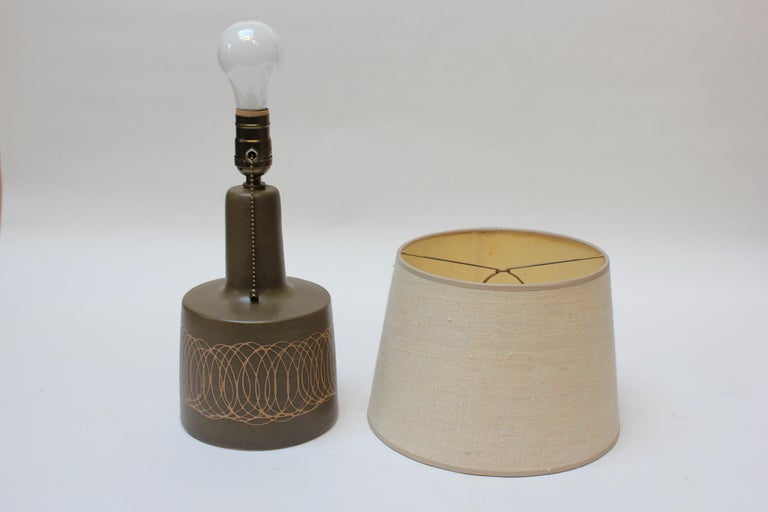 This petite, ceramic table lamp was designed by Gordon and Jane Martz for Marshall Studios in the 1960s. The matte brown finish (which actually appears army green depending on the light / angle) features a heavily mottled surface and overlapping