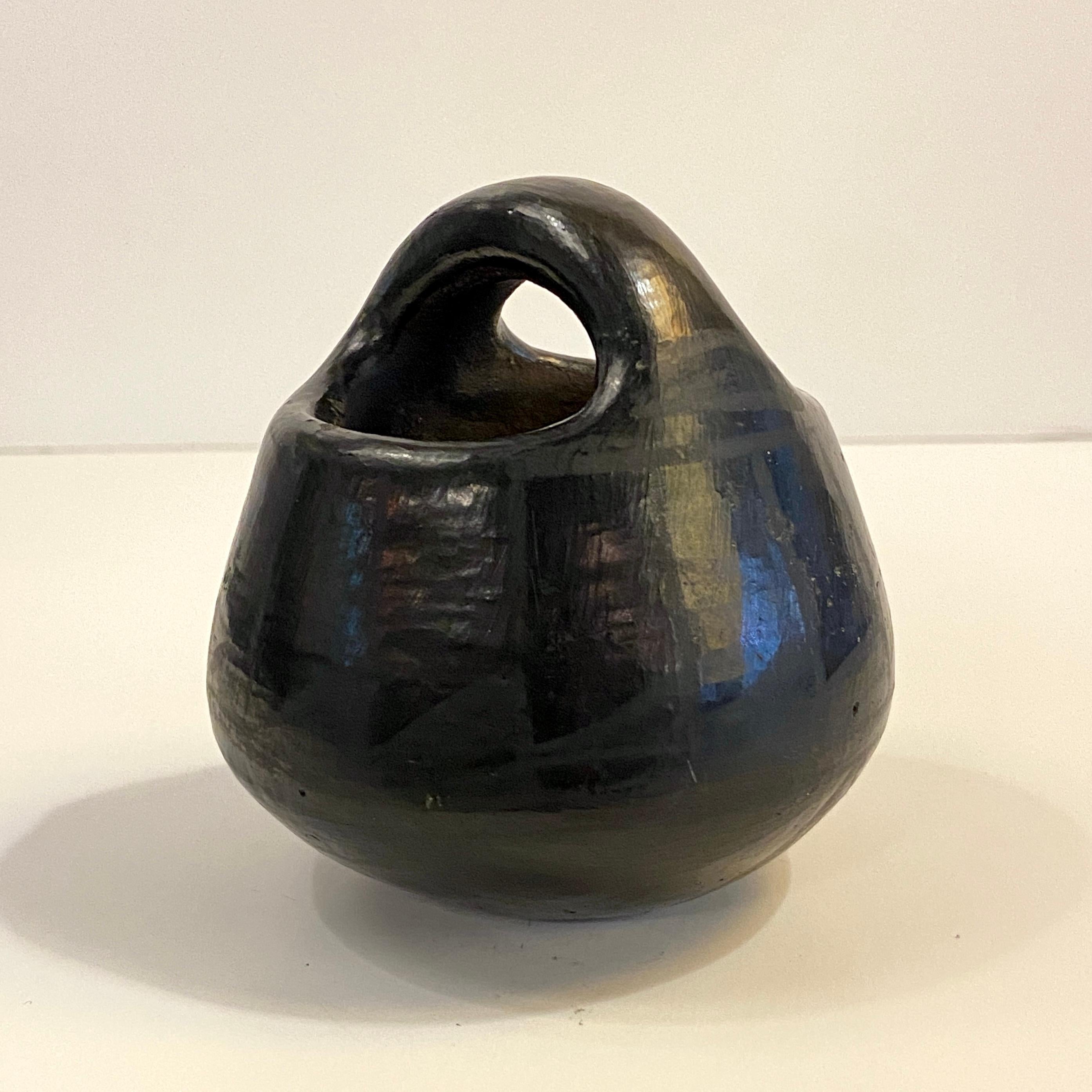 Petite, mid-century, handmade Native American art pottery vessel in the shape of a basket by Josefina Martinez of Santo Domingo Pueblo, New Mexico features a smooth, round surface in semi-gloss, black glaze with a subtle pattern. Signed JM SDP,