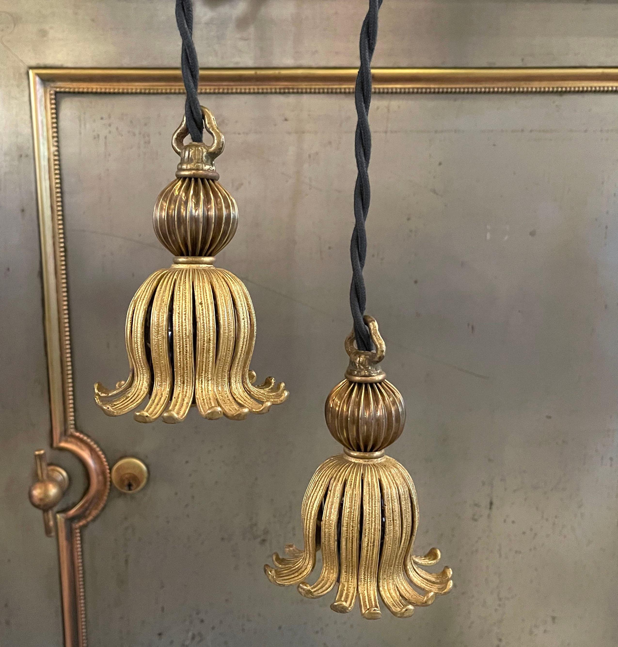 Pair of petite and whimsical, Hollywood Regency, brass tassle, fitter pendants are newly wired with braided cloth cord and ready to receive the decorative bulbs of your choice. Their overall height is 60.5 inches.