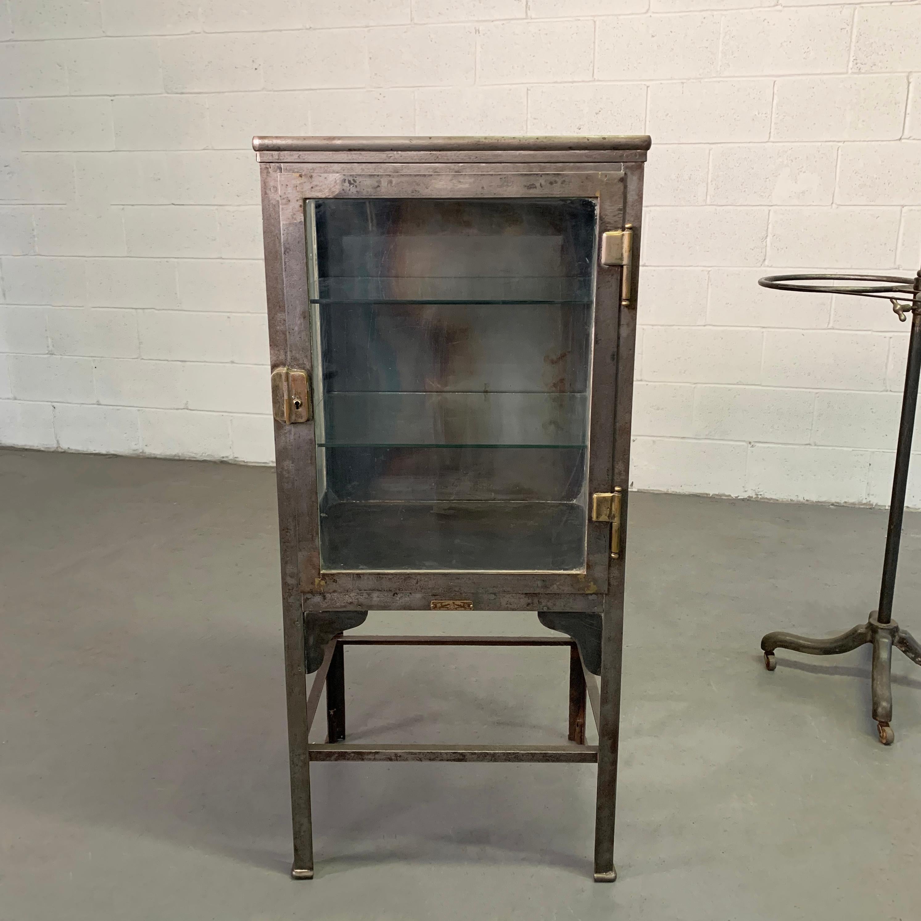 Nicely sized, petite, early 20th century, industrial, apothecary cabinet by The Hospital Supply Co., New York features a newly brushed, steel frame inside and out with glass on 3 sides and 2 glass shelves. The case itself is 26.5 inches height.