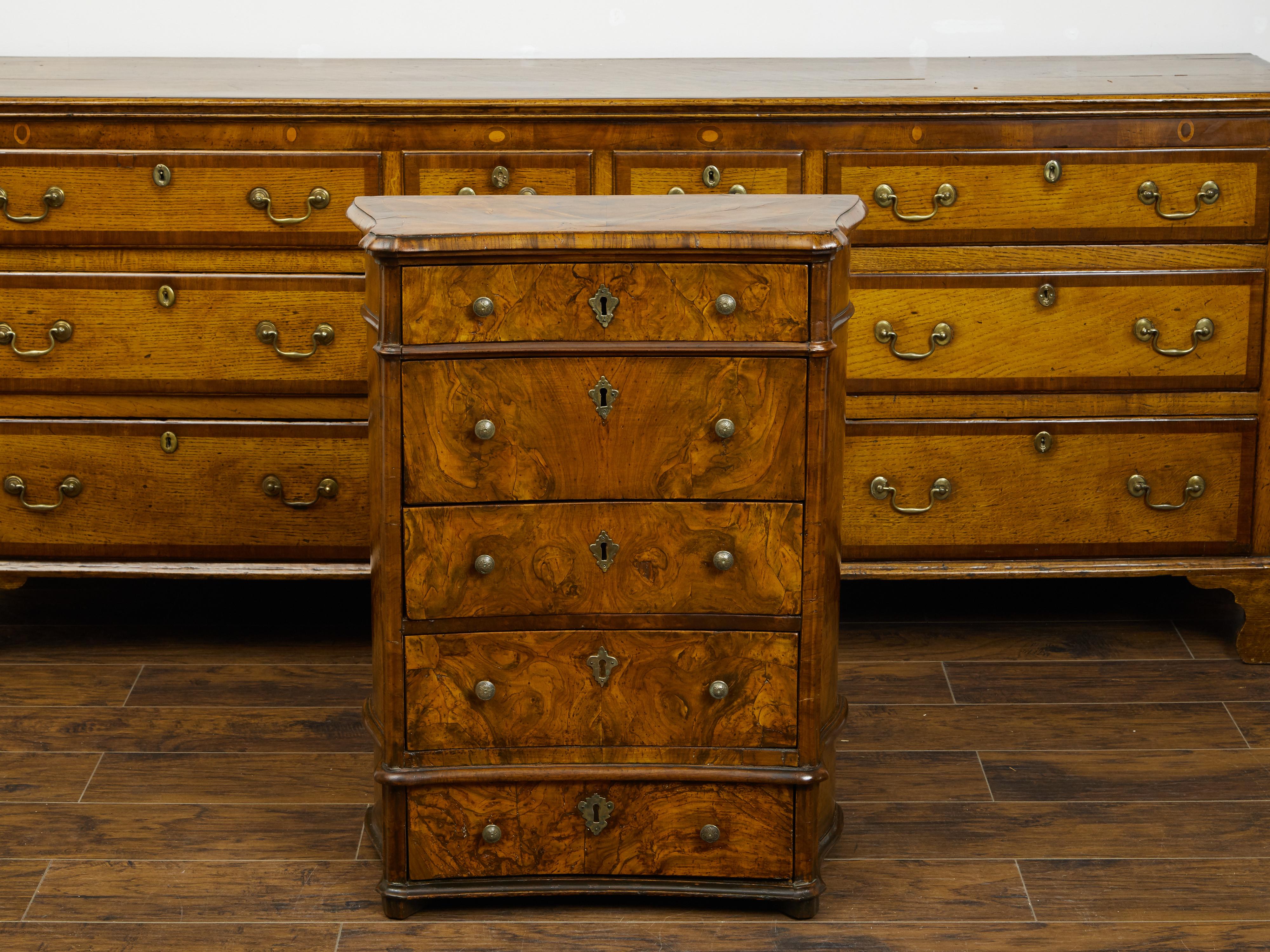 An Italian petite walnut commode from the early 19th century, with butterfly veneer and five drawers. Created in Italy during the first quarter of the 19th century, this petite commode features a rectangular top with serpentine sides, adorned with a