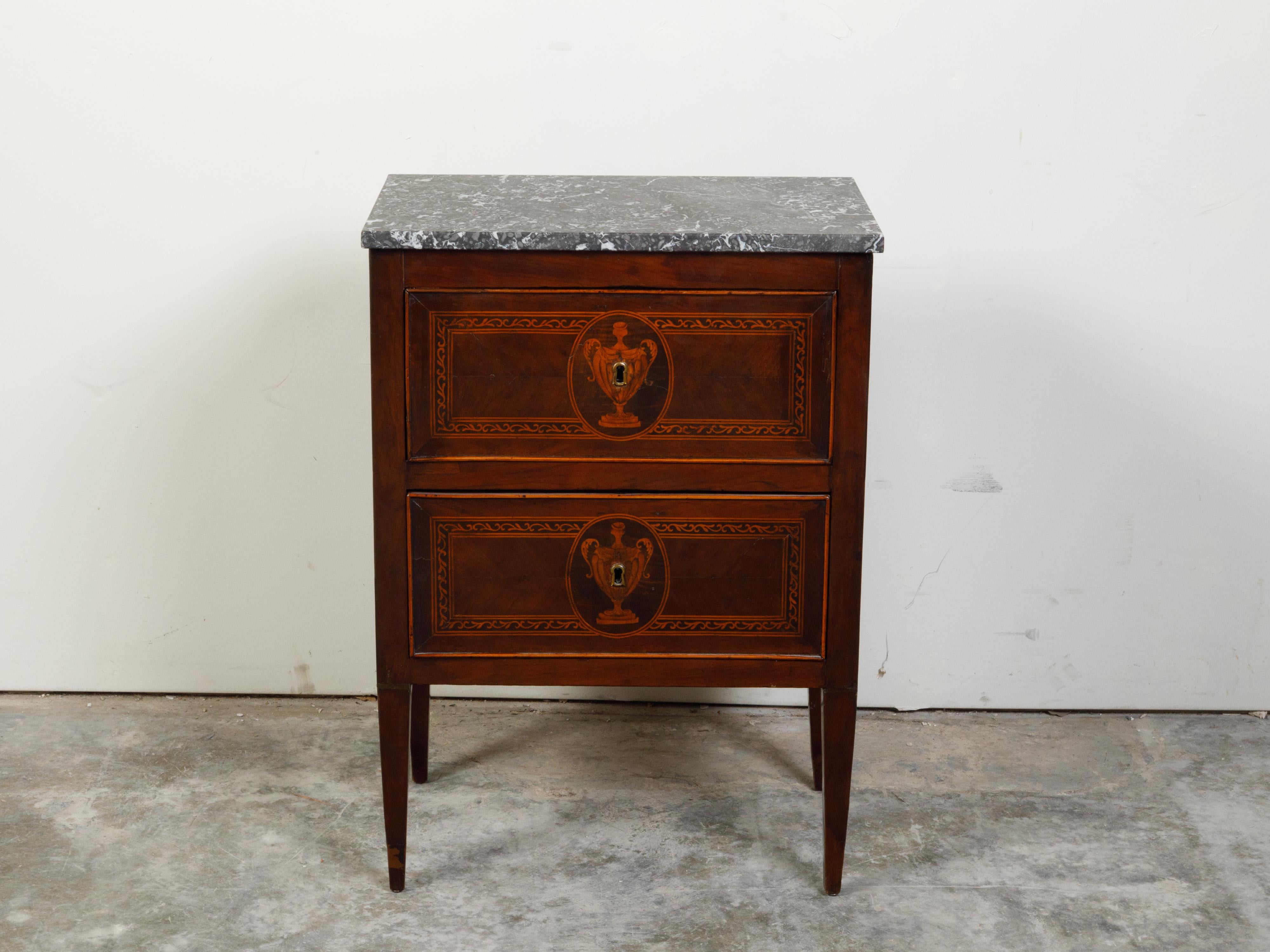 An Italian Neoclassical period walnut commode from the 18th century, with grey marble top and marquetry. Created in Italy during the 18th century, this petite Neoclassical walnut commode features a rectangular grey marble top sitting above two