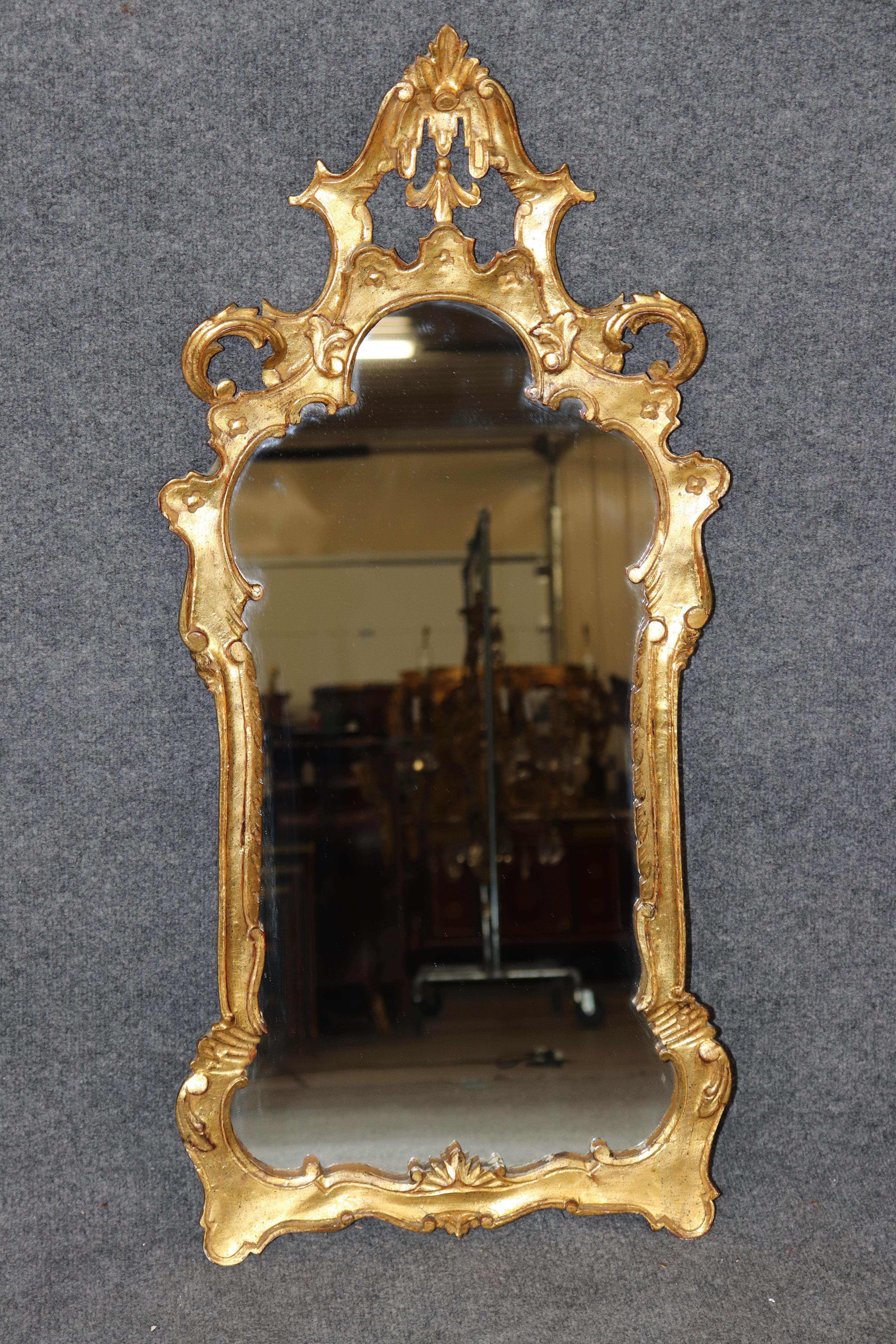 Dimensions - H : 38 1/4 in W : 18 po D : 2 po

Ce charmant petit miroir italien en bois doré de style CIRCA, fabriqué vers les années 1940, capture l'élégance fantaisiste et les ornements du design du XVIIIe siècle à une échelle plus intime et plus