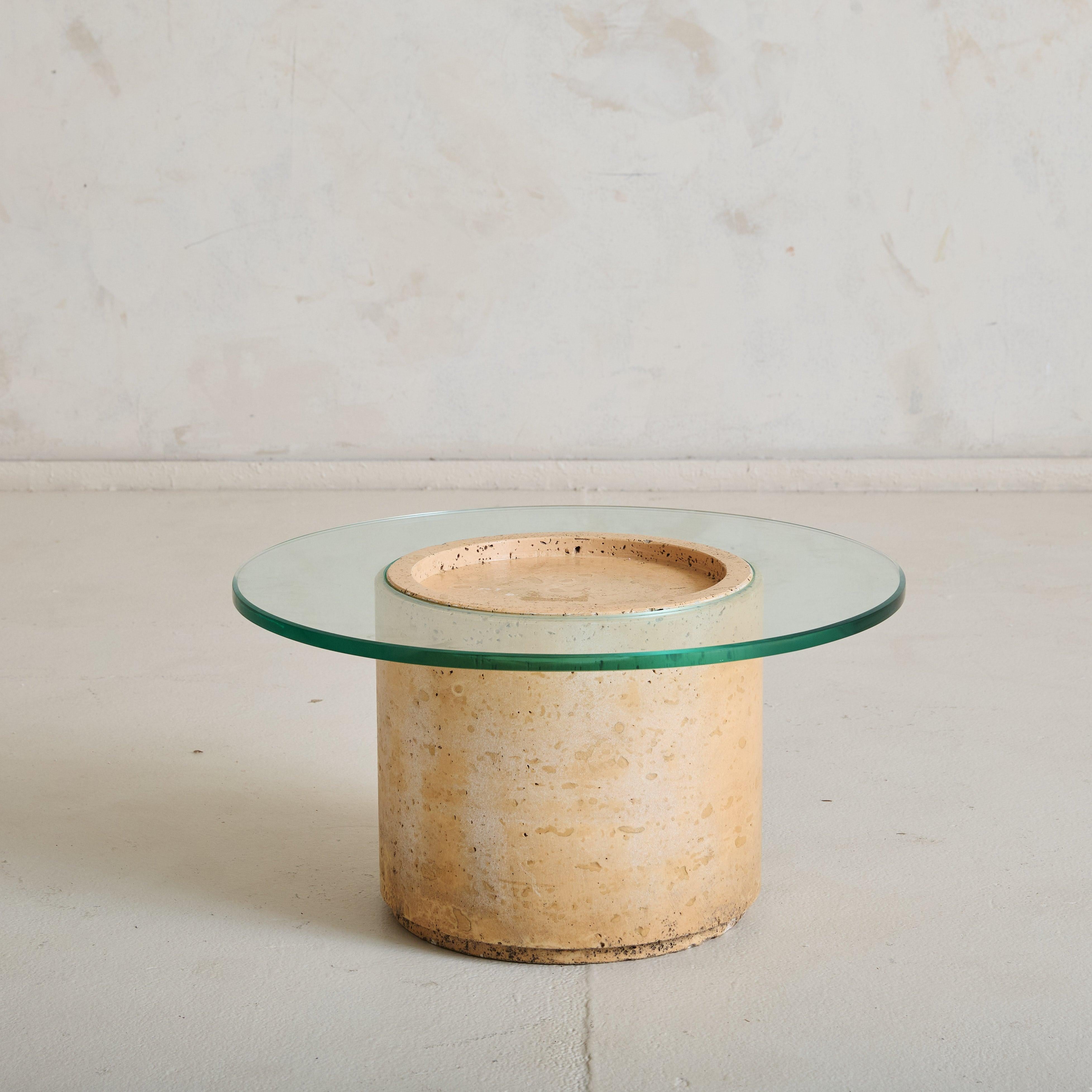 A petite 1960s Italian accent table featuring a cylindrical travertine pedestal base with elegant veining and a porous finish. We love the central inset surface and delicate carvings along the circumference of the base. The natural stone, with its