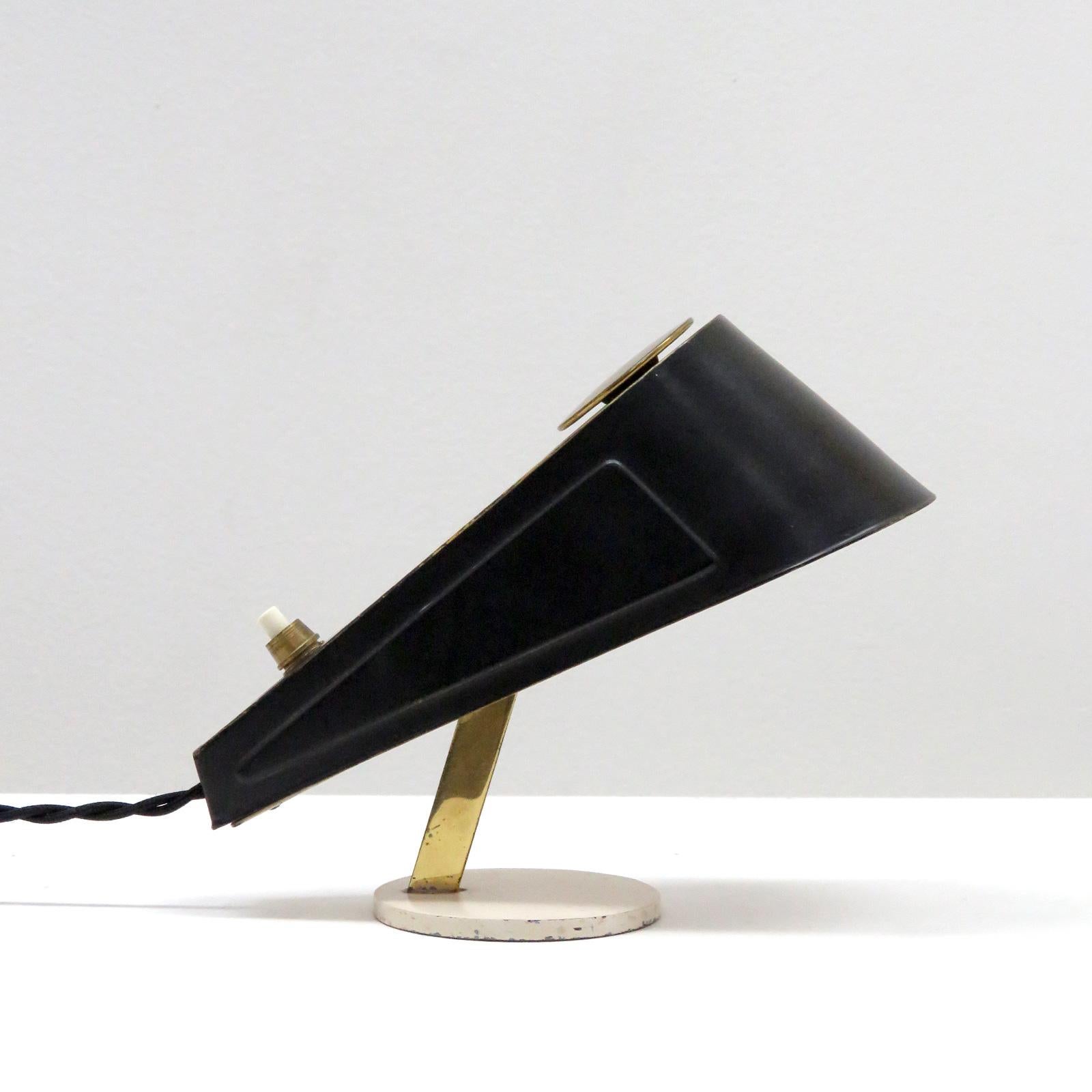 Unique petite Italian table lamp from the 1960s in brass and black and off-white enameled metal, on/off switch at rear of the adjustable body.