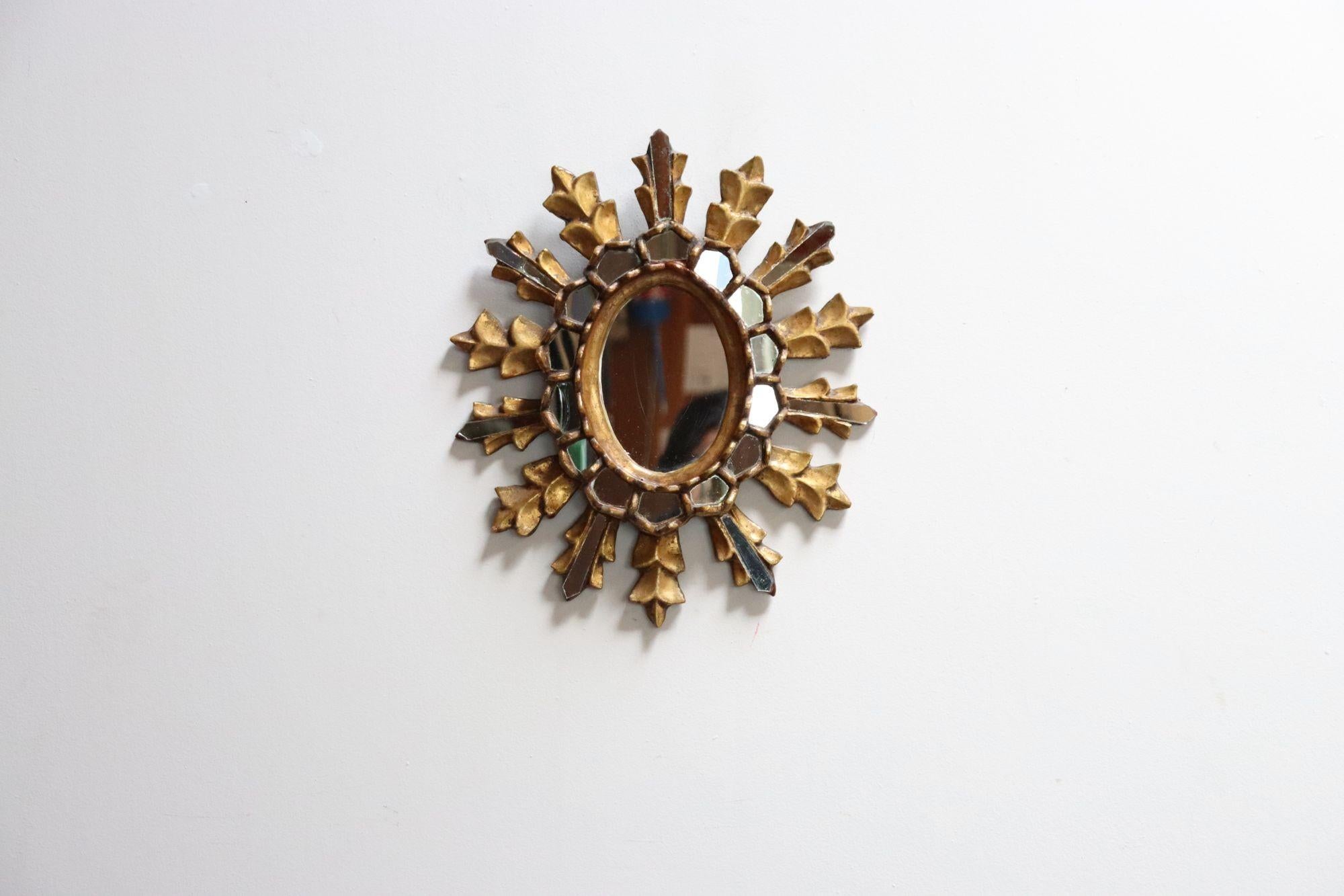 Verkleinerter Wandspiegel aus vergoldetem Holz, geschnitzt in Form von Blattwerk, mit eingesetztem Spiegelglas (ca. 1940er Jahre, Italien).
Originalzustand mit Mängeln am Glas (Risse an einigen der kleineren Einsätze), wie abgebildet, sowie