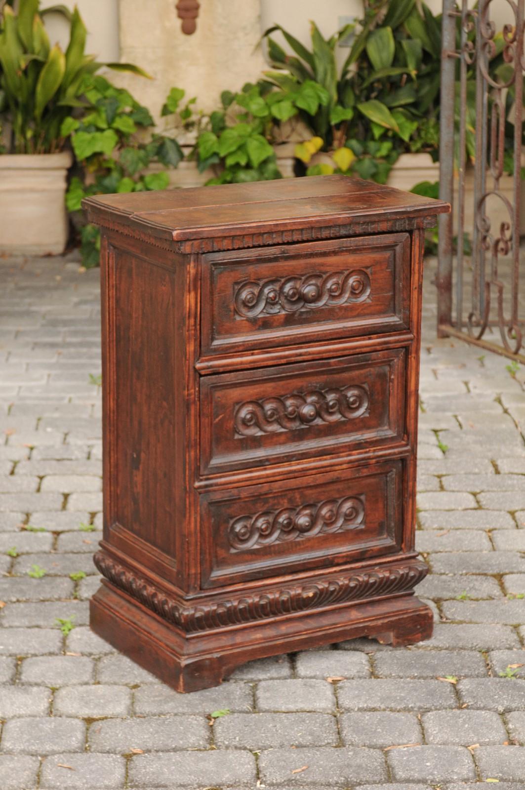 An Italian walnut petite commode from the mid-19th century, with three drawers and guilloche motifs. Born in Italy during the 1st half of the 19th century, this exquisite commode features a rectangular planked top with carved molding, sitting above