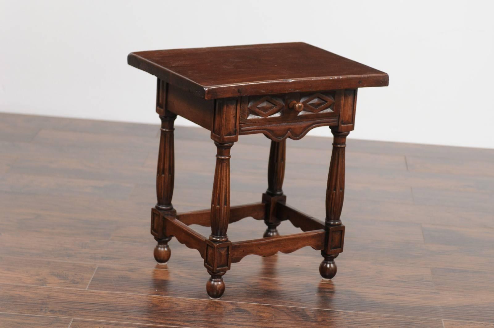 An Italian petite carved walnut side table with single drawer, geometrical motifs, unusual fluted legs and side stretchers from the second half of the 19th century. This Italian walnut side table features a rectangular top sitting above a single