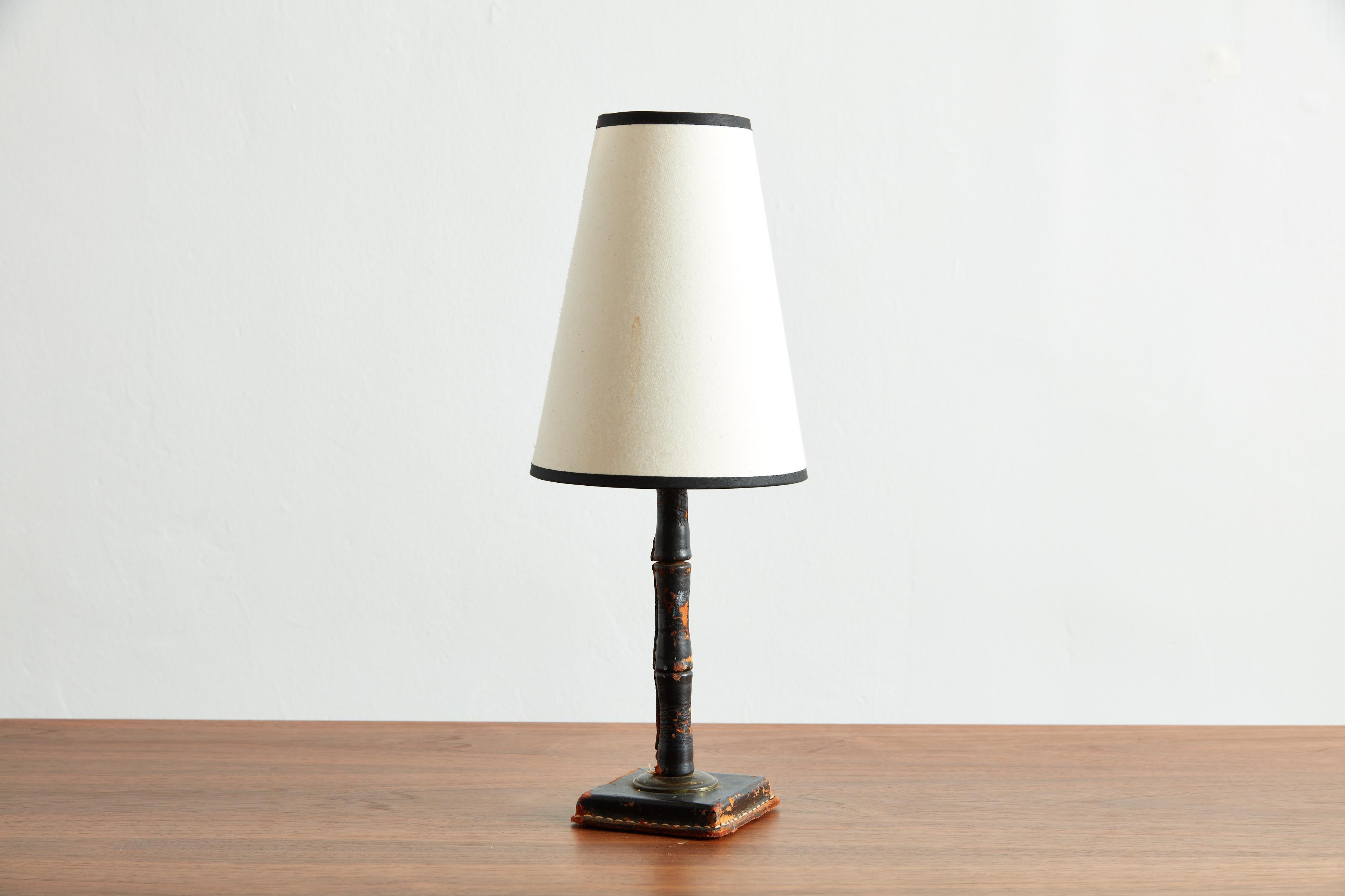 Petite Jacques Adnet black leather table lamp with contrast stitching and wonderful worn patina. 
Original shade.