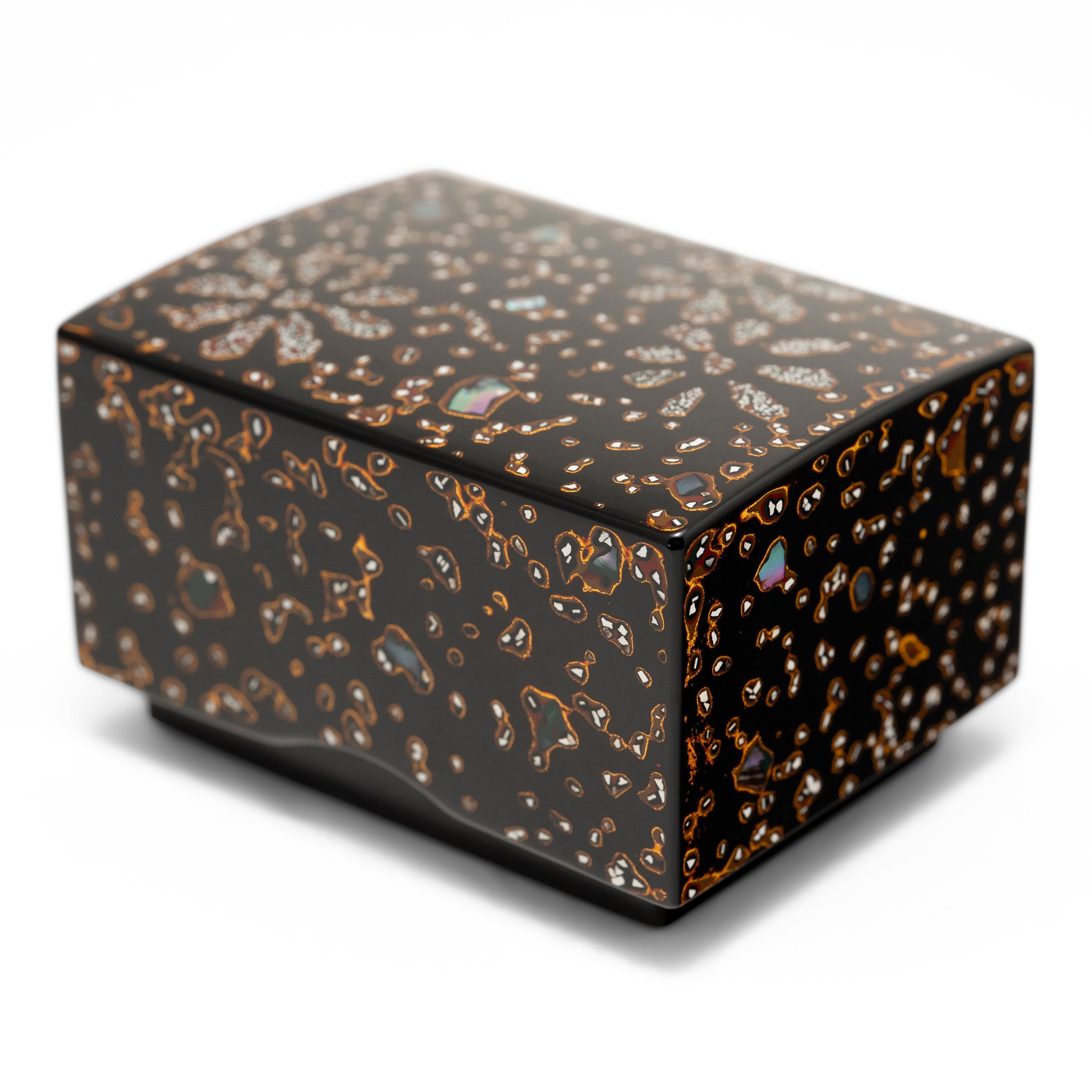 Cette petite boîte à souvenirs japonaise est décorée selon une technique de laque traditionnelle appelée tsugaru-nuri, dans laquelle de la laque parsemée de morceaux de coquillages et de poudre d'or est soigneusement versée sur un support en bois et