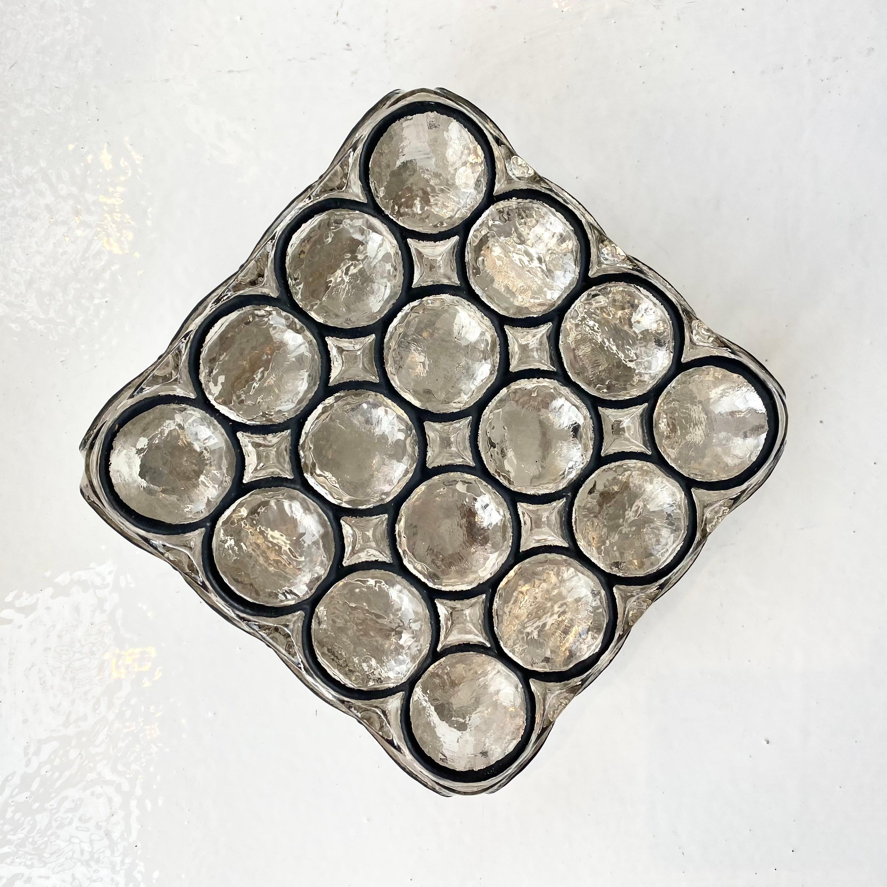 Petite Limburg flush mount or wall sconce. Circa 1960s. Illuminates beautifully with iron circles inlaid in thick square glass. This gorgeous design is based on the traditional church window patterns of European cathedrals and churches.