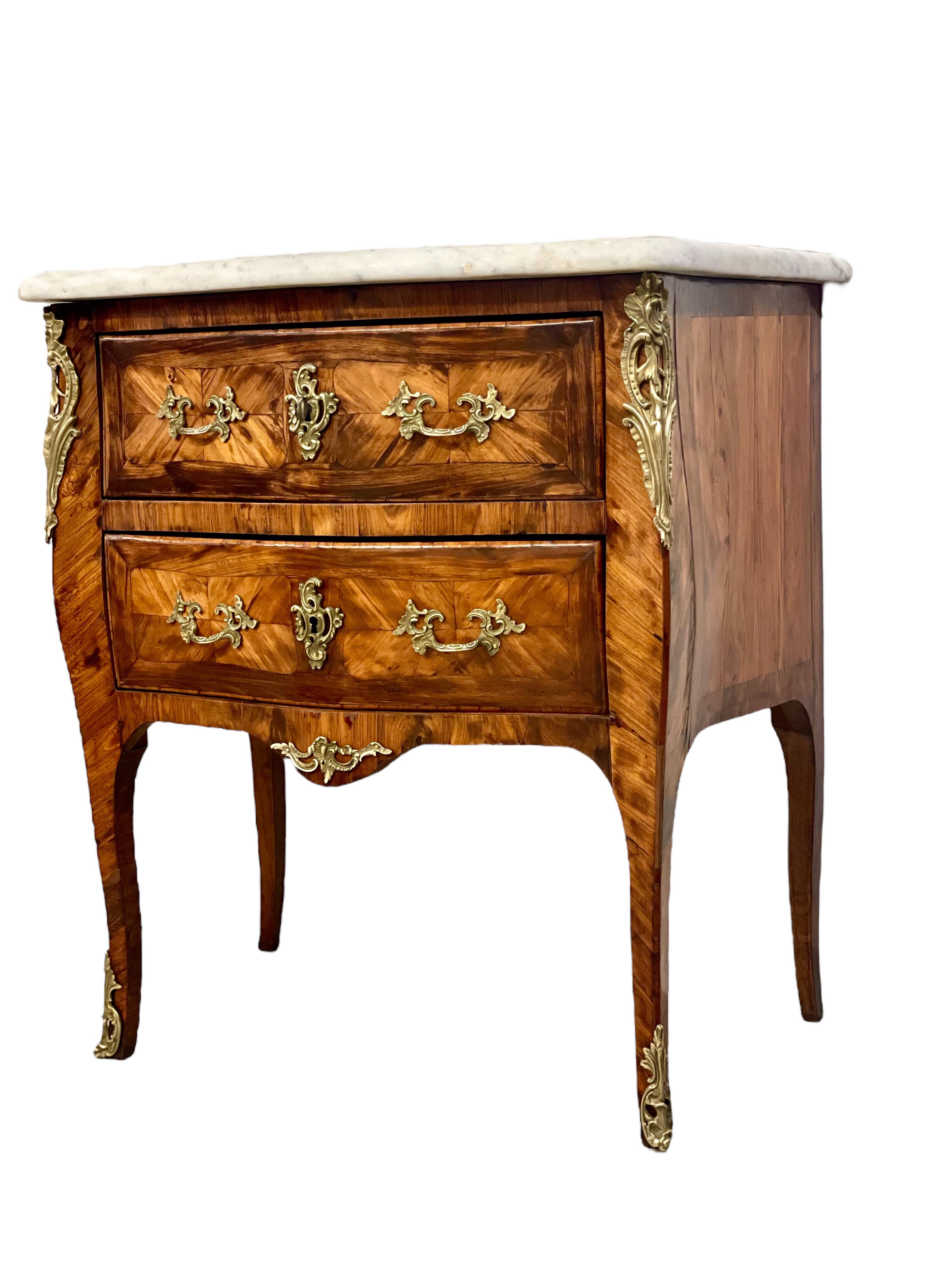 A stylish and petite Louis XV style two-drawer marquetry commode, with a curved front and sides and a shaped and polished grey-veined marble top. This very attractive chest of drawers is decorated throughout with intricate diagonally set veneers,