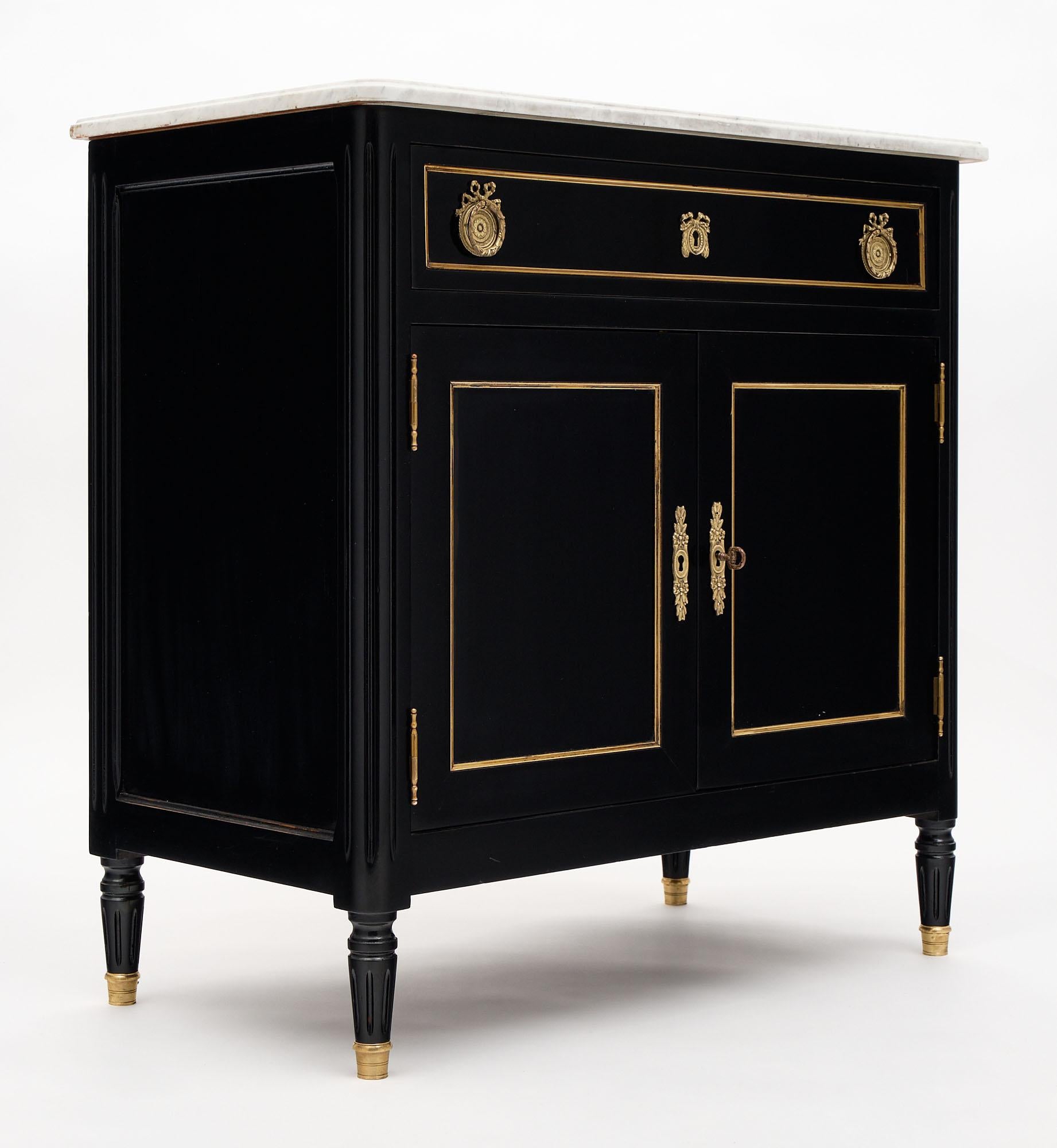 Petite Louis XVI style French buffet made of mahogany and ebonized with a lustrous French polish museum-quality finish. The buffet is topped with a Carrara marble slab. This small cabinet features a single dovetailed drawer above two doors which