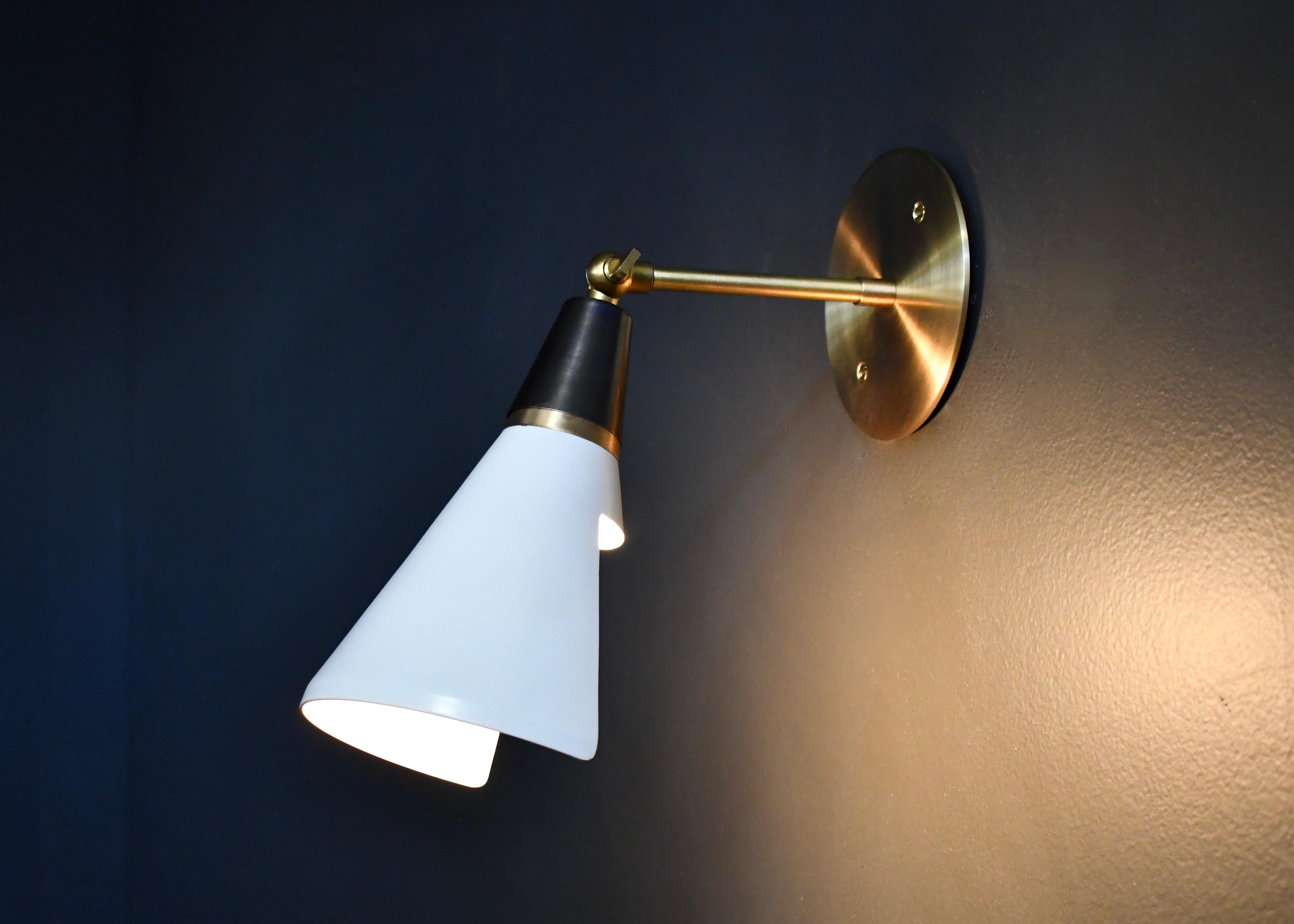 The Petite Magari wall lamp or sconce is handmade to order by Blueprint Lighting. The shade has a swivel mechanism for rotation. This design is strongly influenced by both French and Italian Mid-Century Modernism and features a distinctly beveled