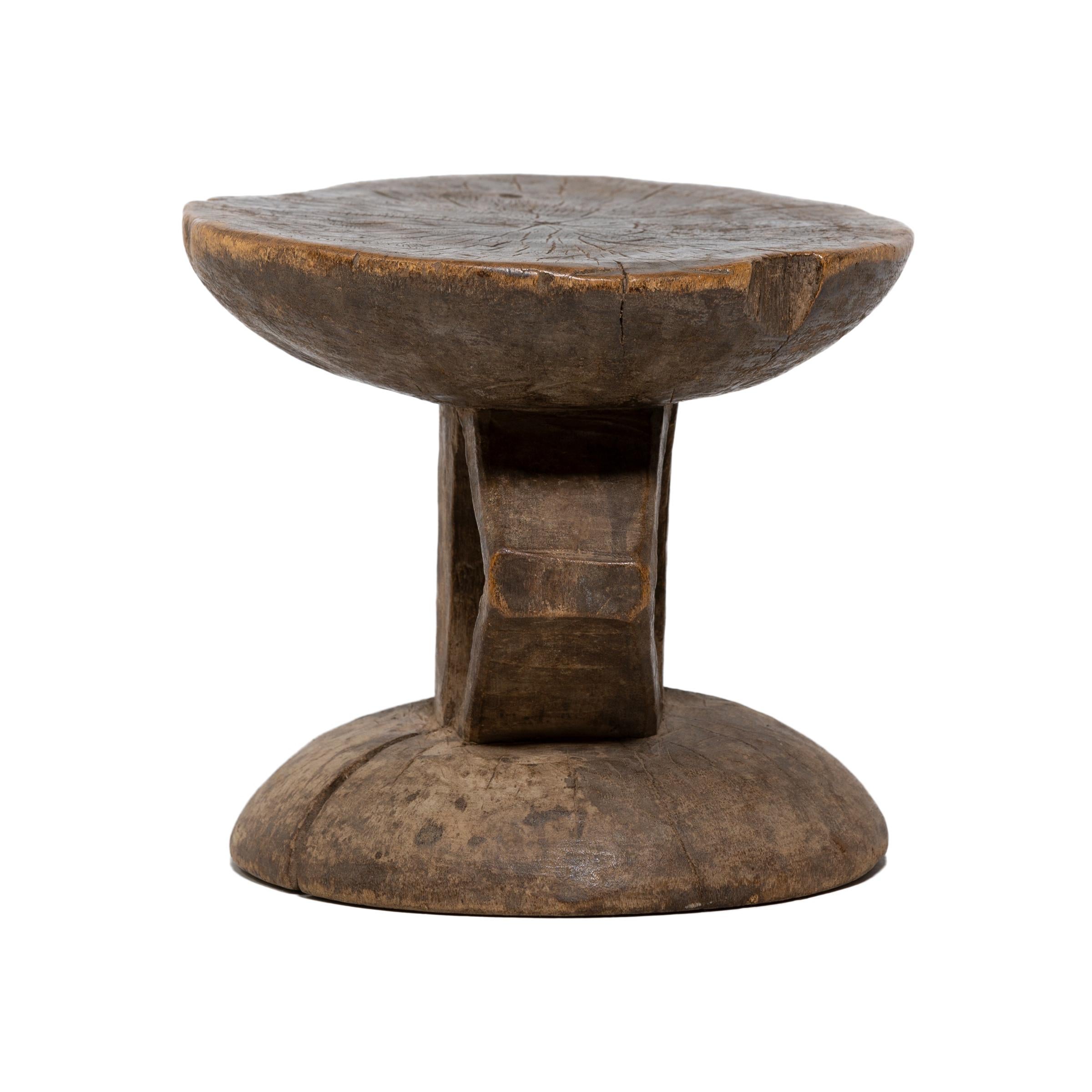 Unlike the figurative nommo stools used by elders, this petite stool by the Dogon peoples of Mali would have been used for everyday seating. The domed seat and base are connected by a central post flanked by two angular supports. The triangular